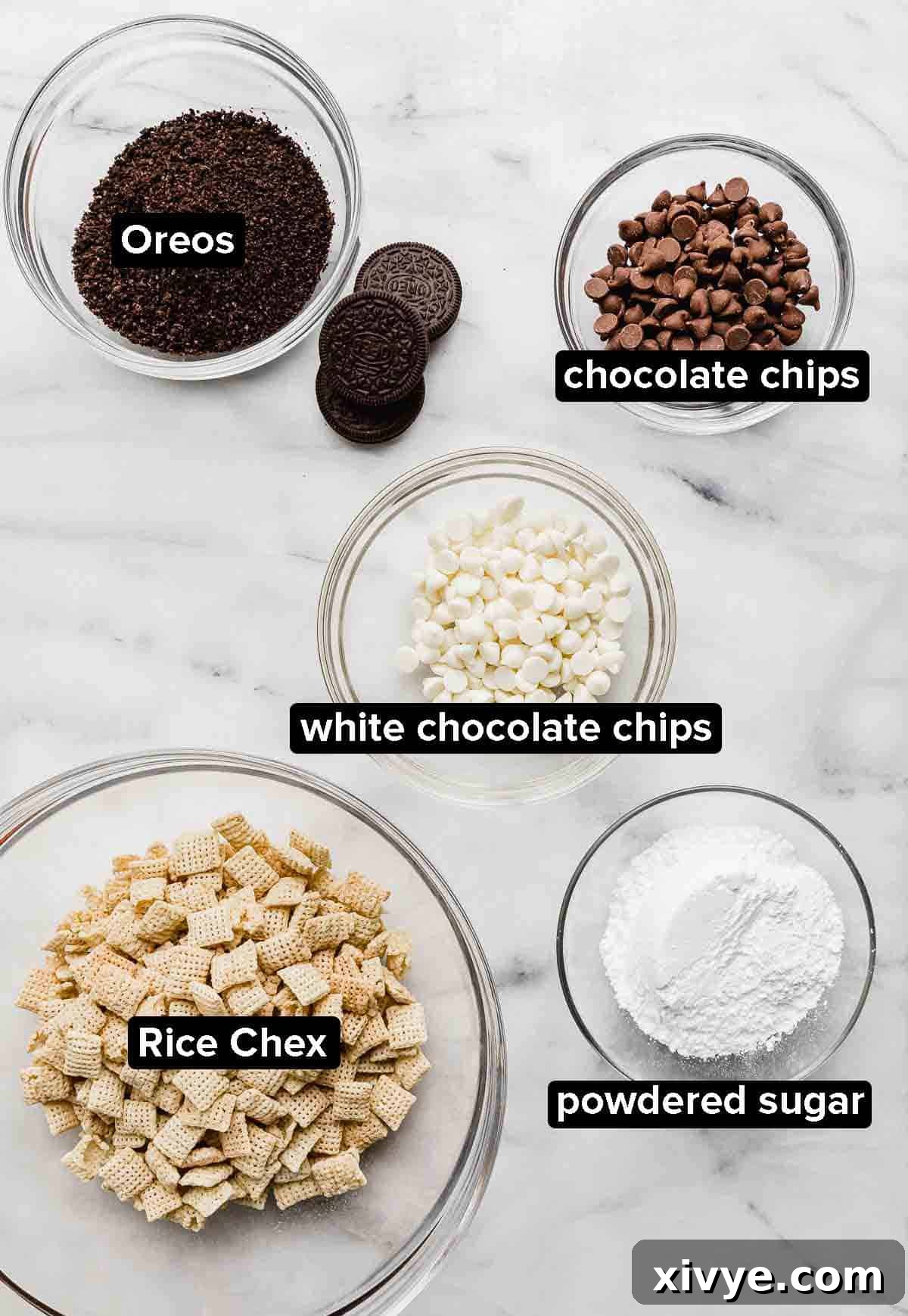 Oreo Muddy Buddies ingredients on a white marble background: Oreo crumbs, Chex cereal, white and milk chocolate chips, and powdered sugar.