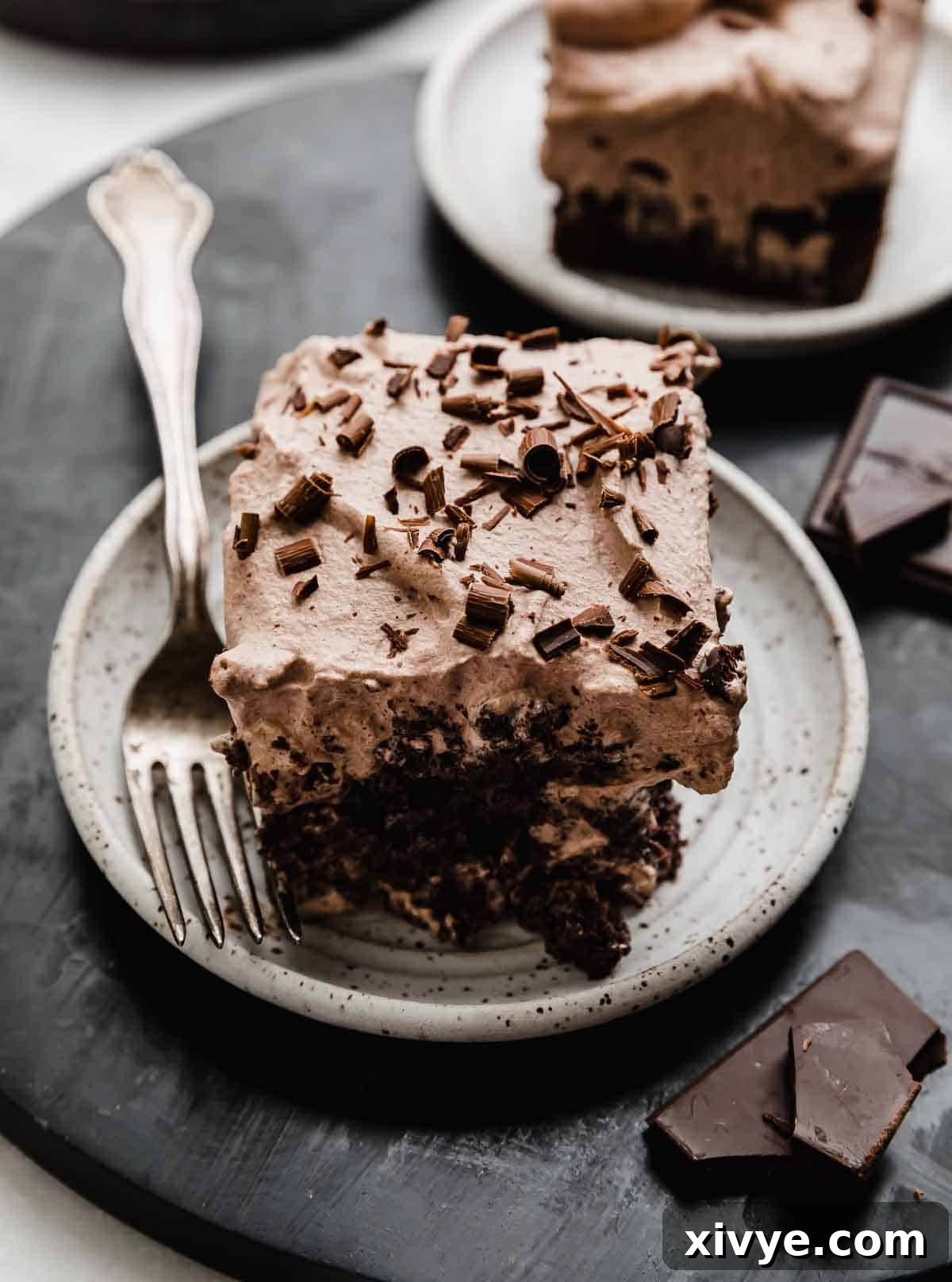 Heavenly Chocolate Tres Leches Cake 7 Chocolate Tres Leches Cake slice on a white plate with a fork next to the cake slice.
