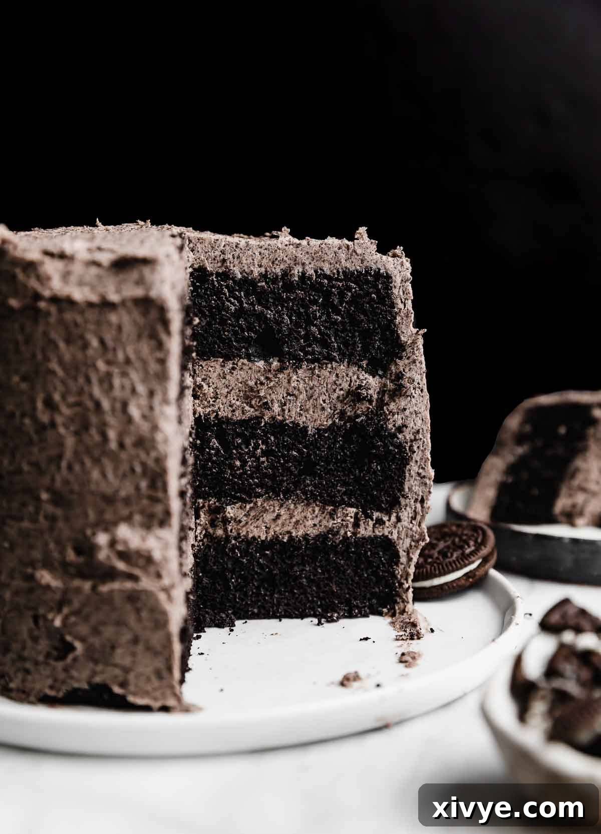 A beautifully decorated three-layer 6-inch Oreo Cake, generously topped with creamy Oreo frosting and garnished with whole Oreo cookies, set against a dark background.