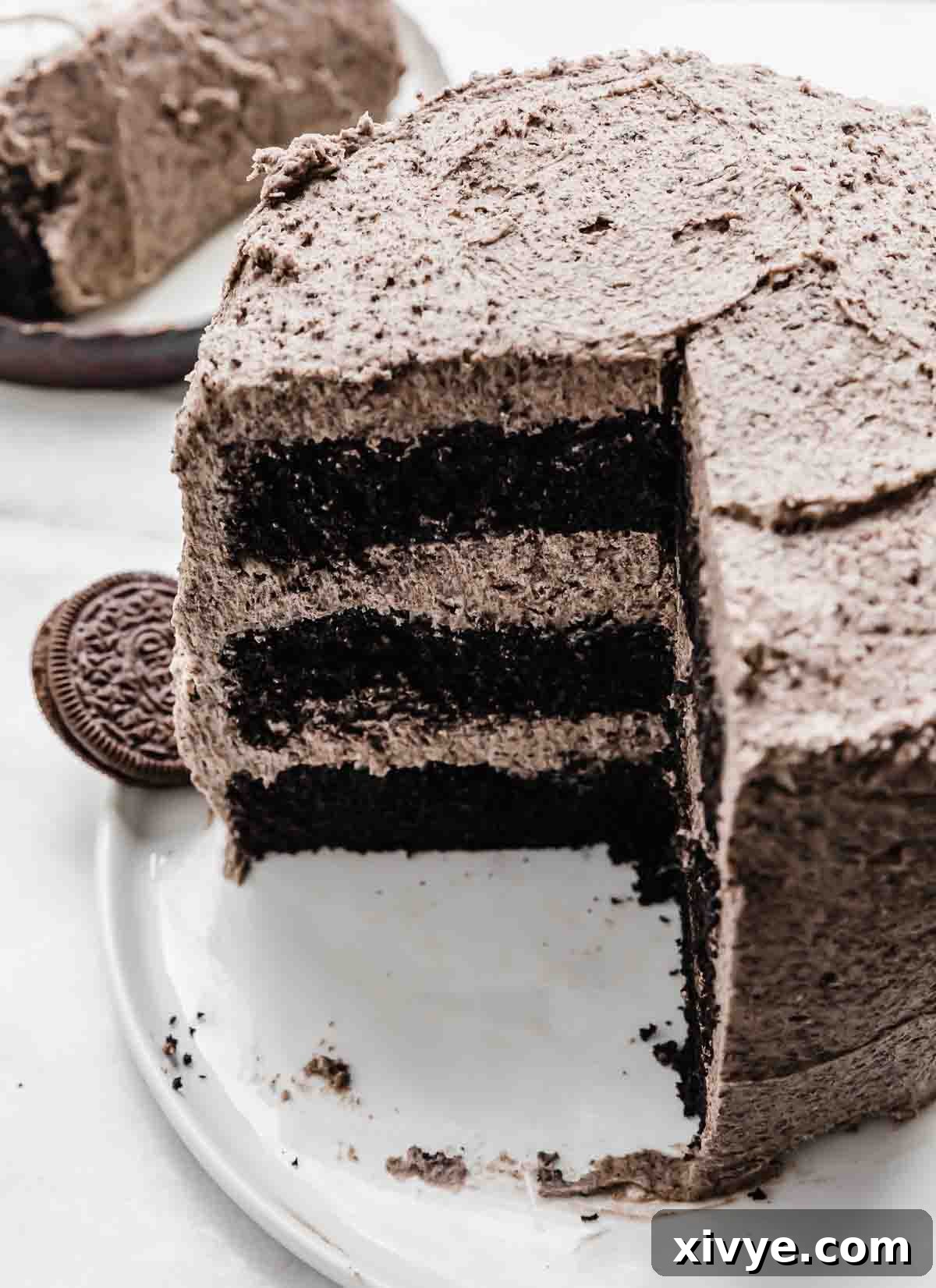 A beautifully presented Oreo Cake recipe on a white plate, with a quarter of the cake elegantly cut and removed, highlighting its perfect layers and inviting texture.