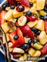 Close-up image of a fruit salad cocktail with a glossy honey lime dressing.
