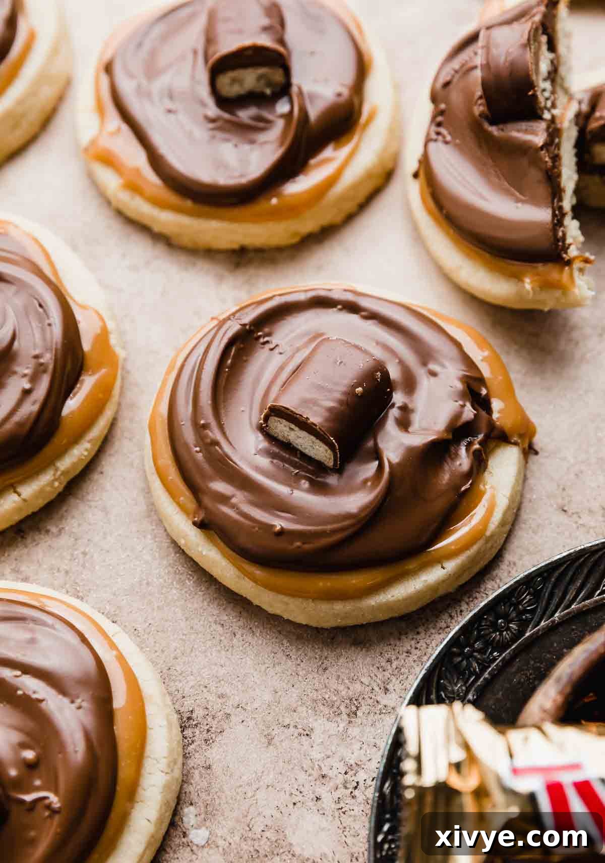 Twix cookies on a light brown background with each cookie topped with a mini Twix bar.