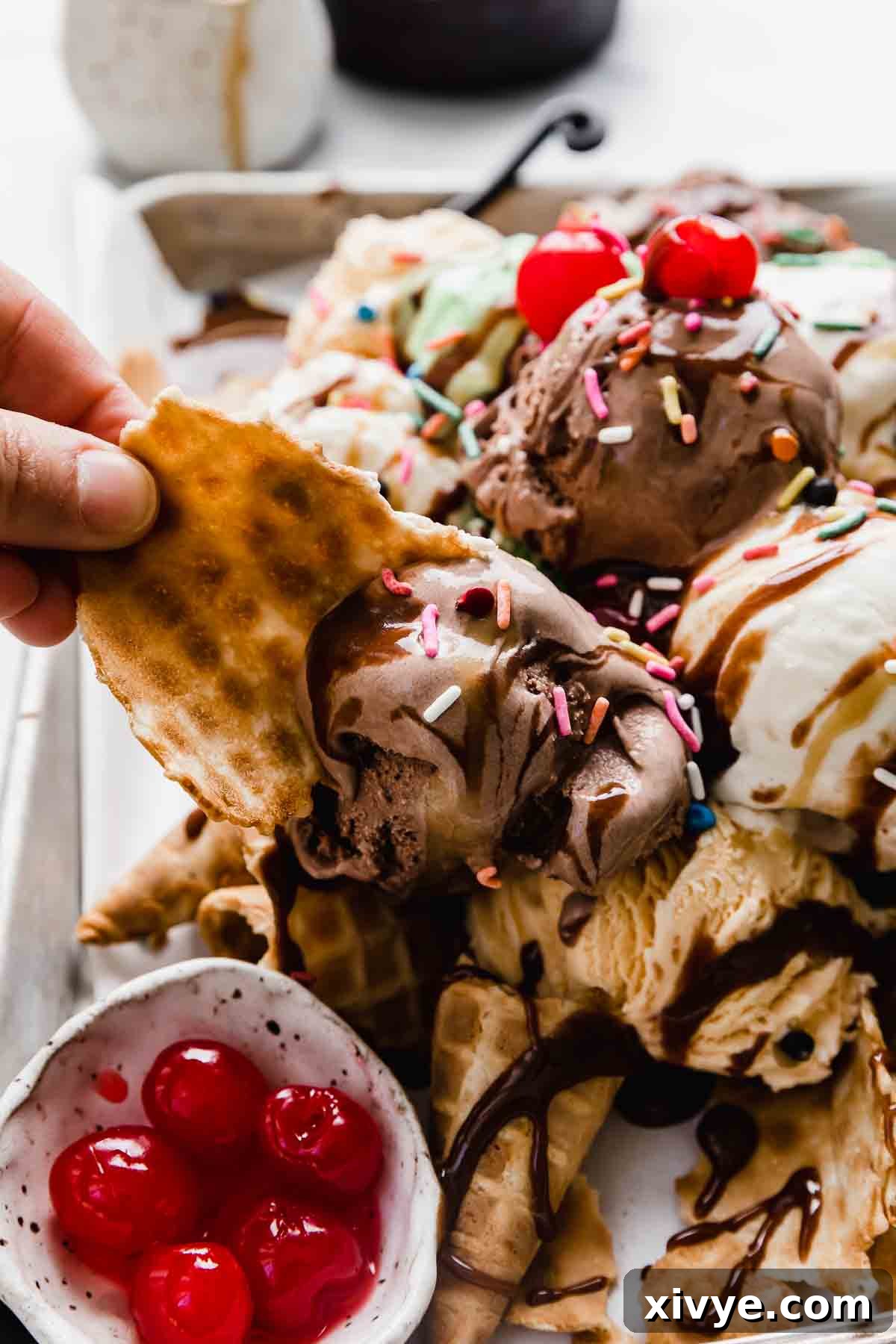 A waffle cone piece being used to scoop of chocolate ice cream.
