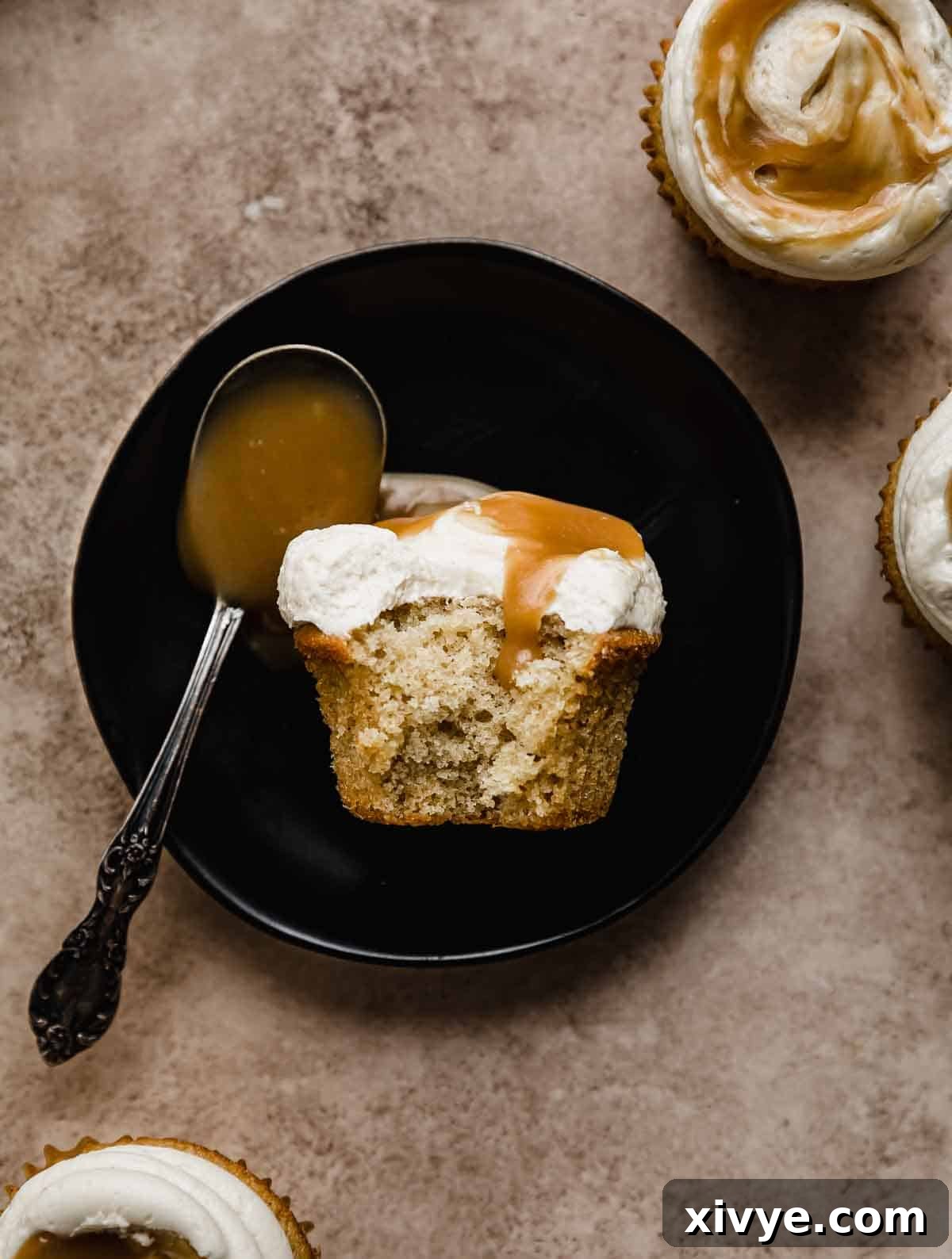 Golden Butterscotch Delights 7 A Butterscotch Cupcake on a black plate with a bite taken from the cupcake.