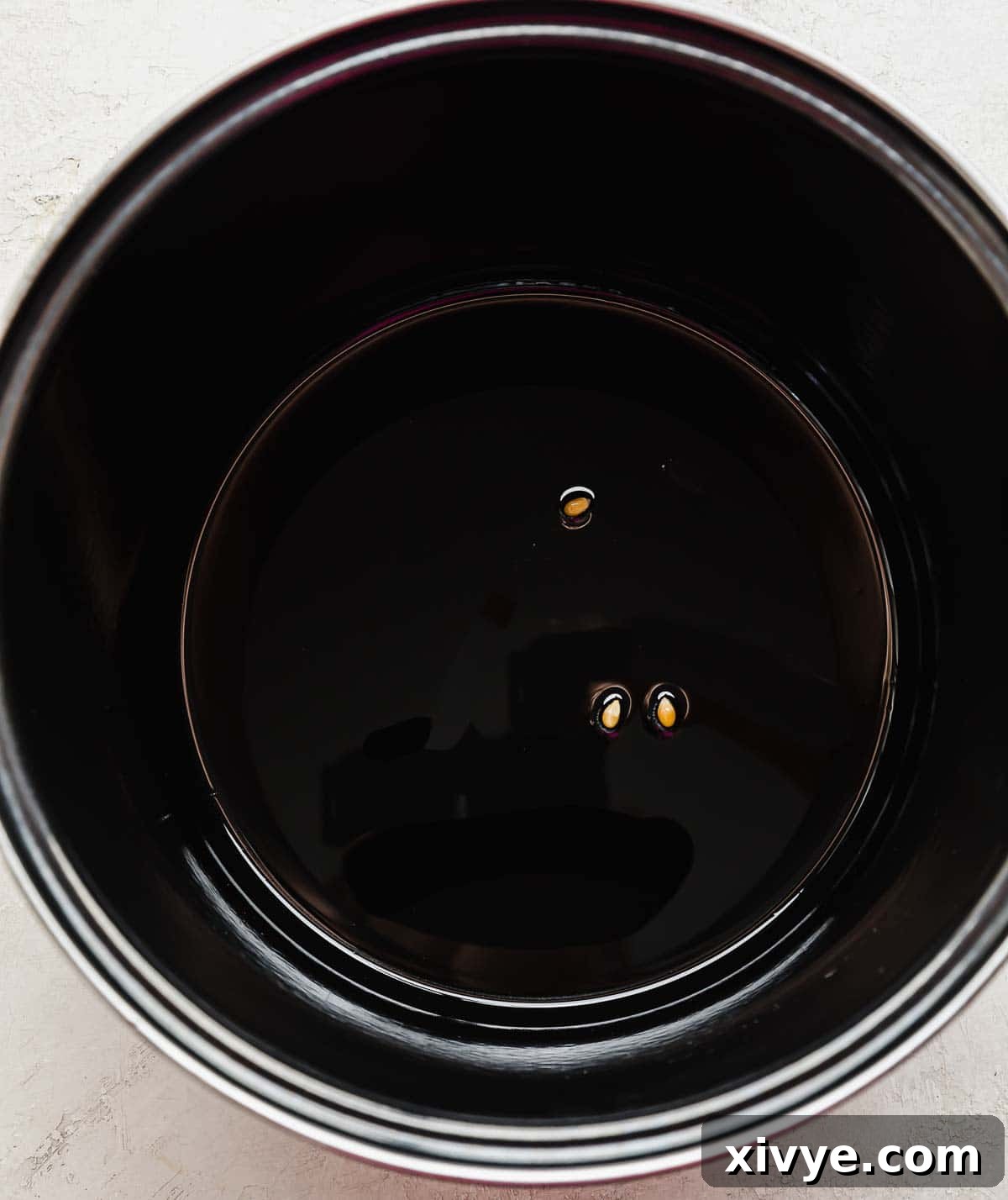 Sweet and Salty Kettle Corn 4 A large black pot containing oil and 3 popcorn kernels, used for testing oil temperature.