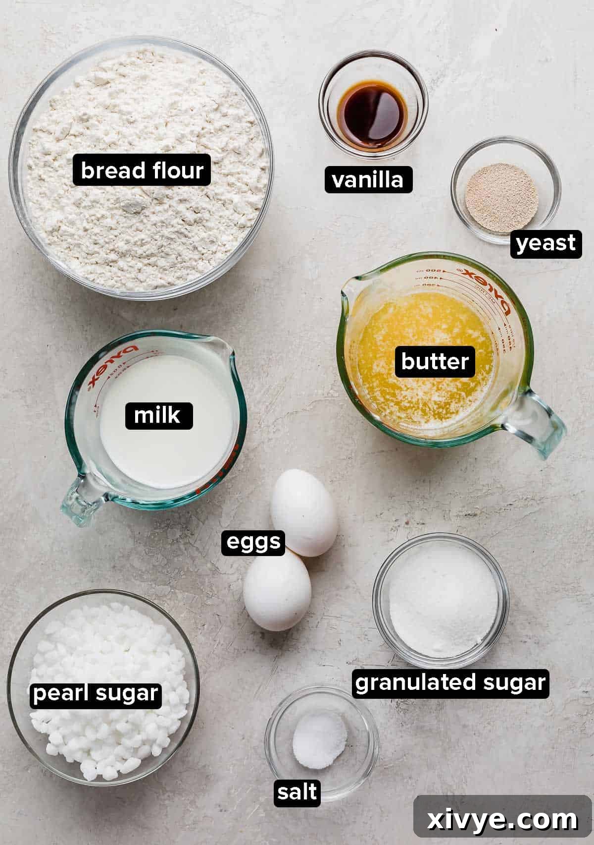 Belgian Liege Waffle ingredients portioned into glass bowls on a light gray background, including milk, yeast, sugar, flour, butter, and pearl sugar.