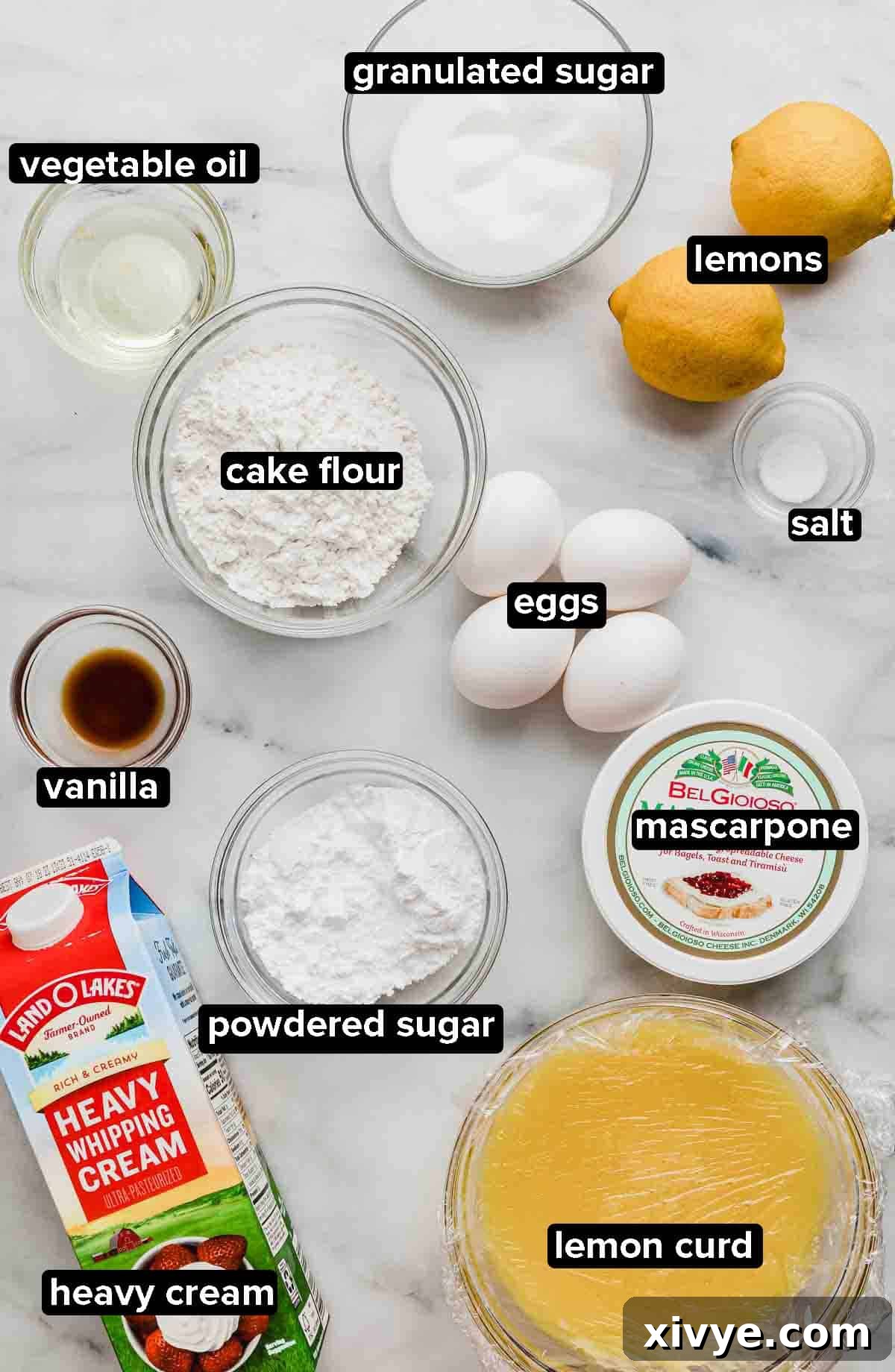 A curated display of ingredients for Lemon Swiss Roll: fresh lemons, granulated sugar, large eggs, vanilla extract, heavy cream, mascarpone cheese, cake flour, and a jar of homemade lemon curd.