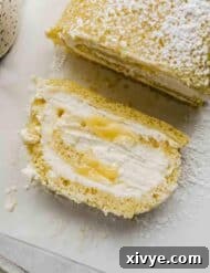 A slice of Lemon Swiss Roll on a white parchment paper.