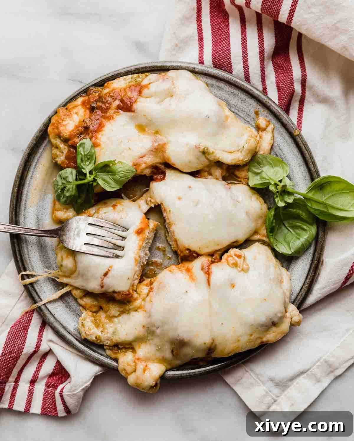 A gray plate topped with 3 pieces of Pesto Chicken Parmesan.