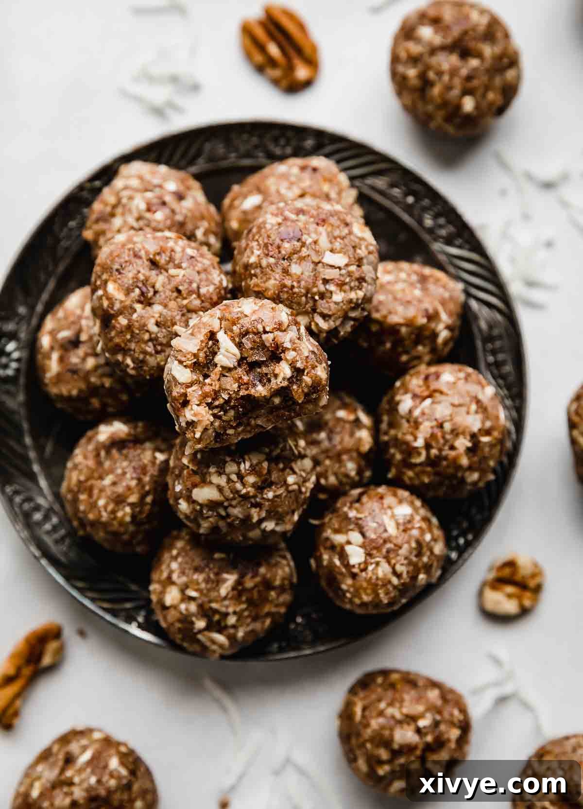 German Chocolate Protein Power Bites 2 German Chocolate Cake Protein Balls stacked on a black plate on a white background.