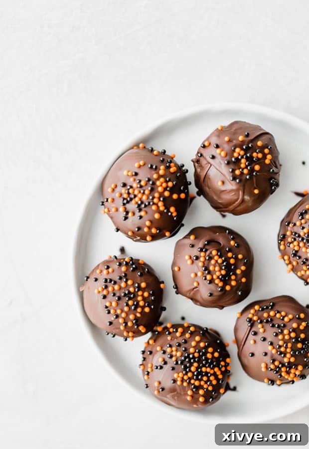 Spooktacular Halloween Oreo Truffles 2 Oreo balls dipped in dark chocolate and covered in orange and black sprinkles.