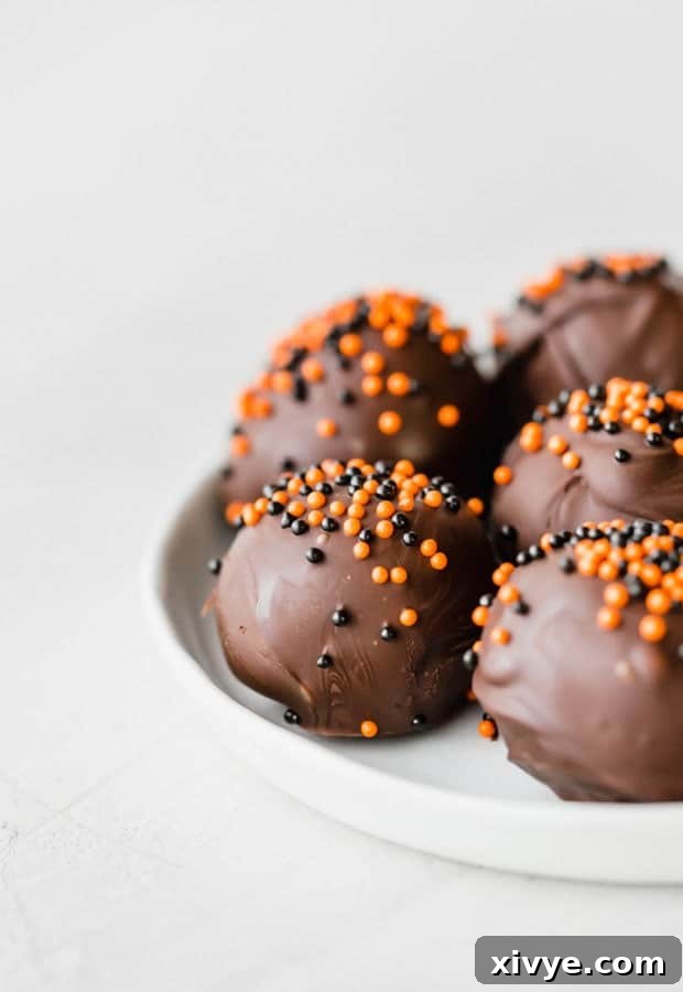Spooktacular Halloween Oreo Truffles 3 Oreo balls covered in dark chocolate and sprinkled with orange and black ball sprinkles.