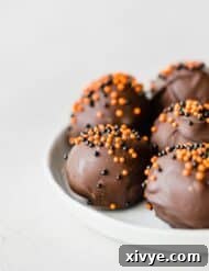 Oreo balls covered in dark chocolate and sprinkled with orange and black ball sprinkles.