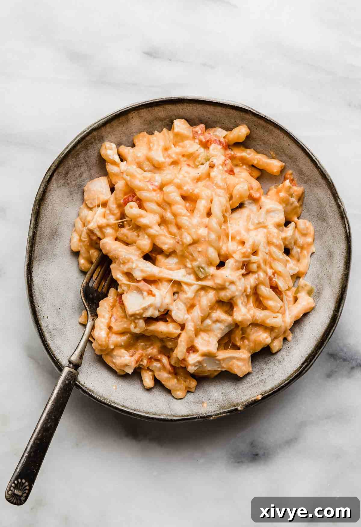 A gray bowl with Buffalo Chicken Pasta, on a white marble background.