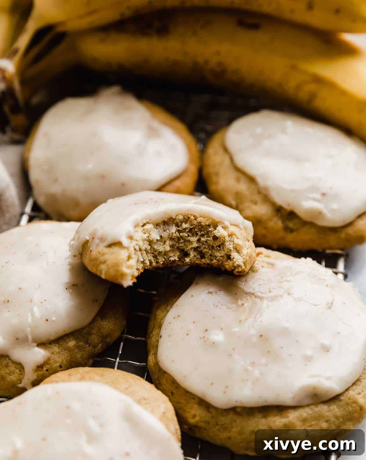 A bite taken out of a banana cookie frosted with brown butter frosting.