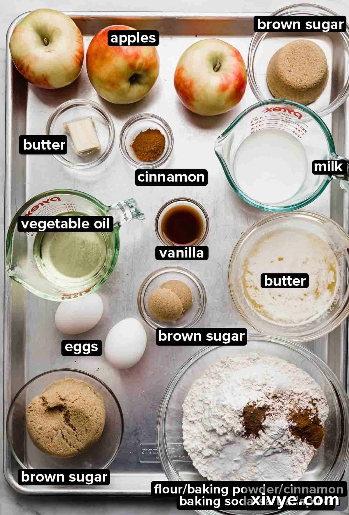 Spiced Apple Fritter Coffee Cake 3 Apple Fritter Cake ingredients portioned into glass bowls on a silver baking sheet: apples, brown sugar, flour, eggs, oil, vanilla, and spices.
