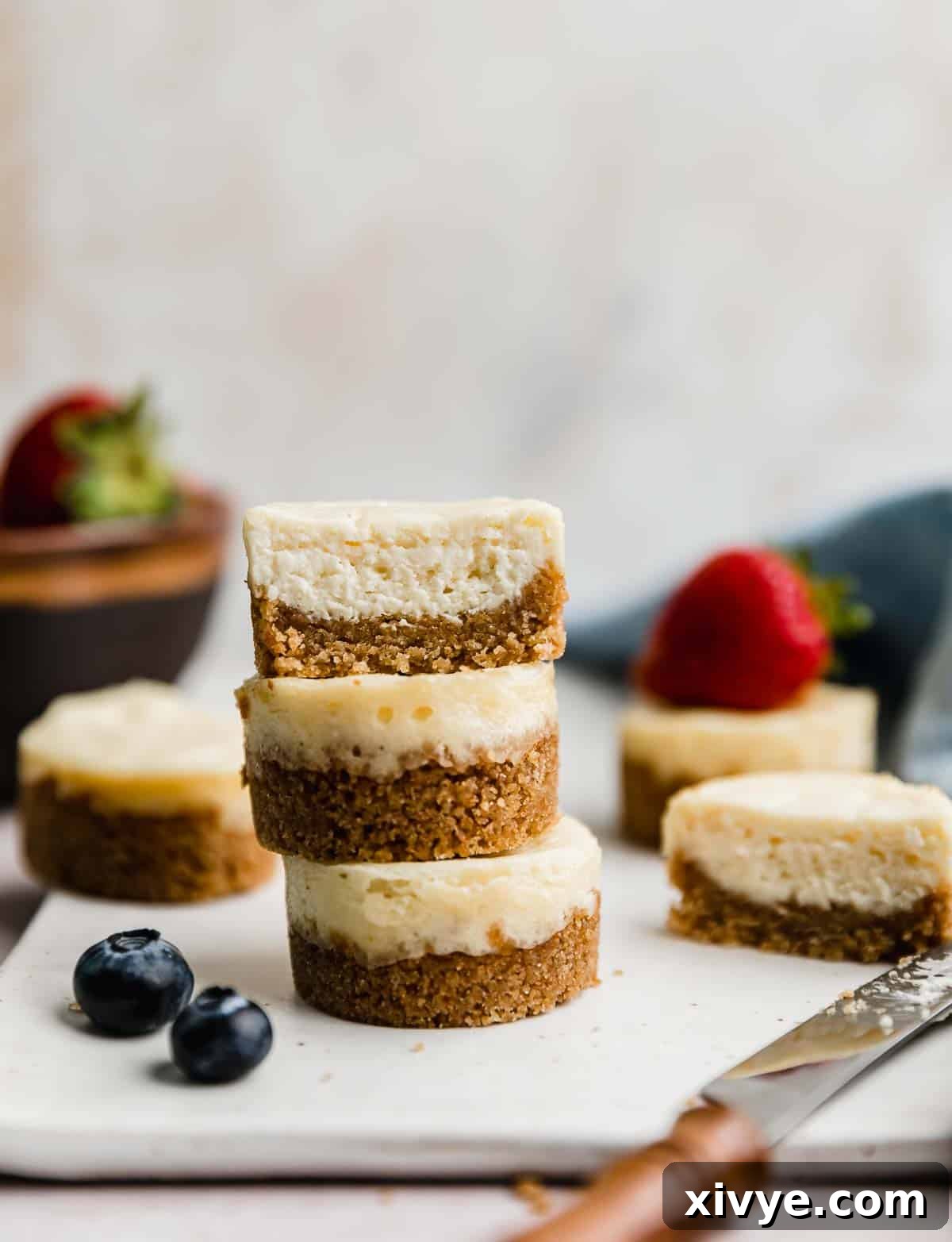 Three Mini Cheesecakes stacked on top of each other against a light cream background.