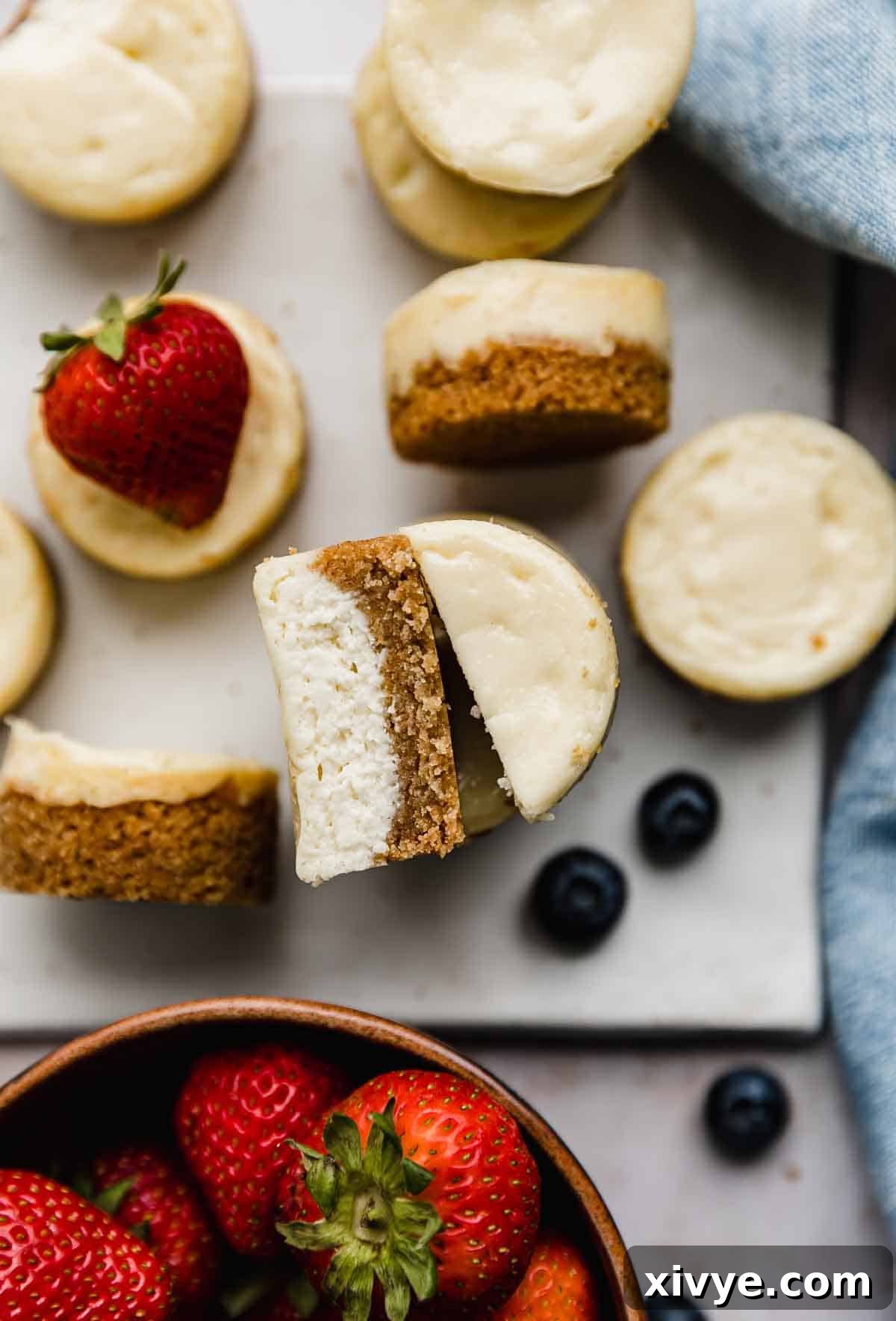 Mini Cheesecakes on a white plate with strawberries and blueberries surrounding the mini desserts.