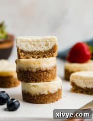A mini cheesecake cut in half, and stacked on two additional small cheesecakes on a white plate.
