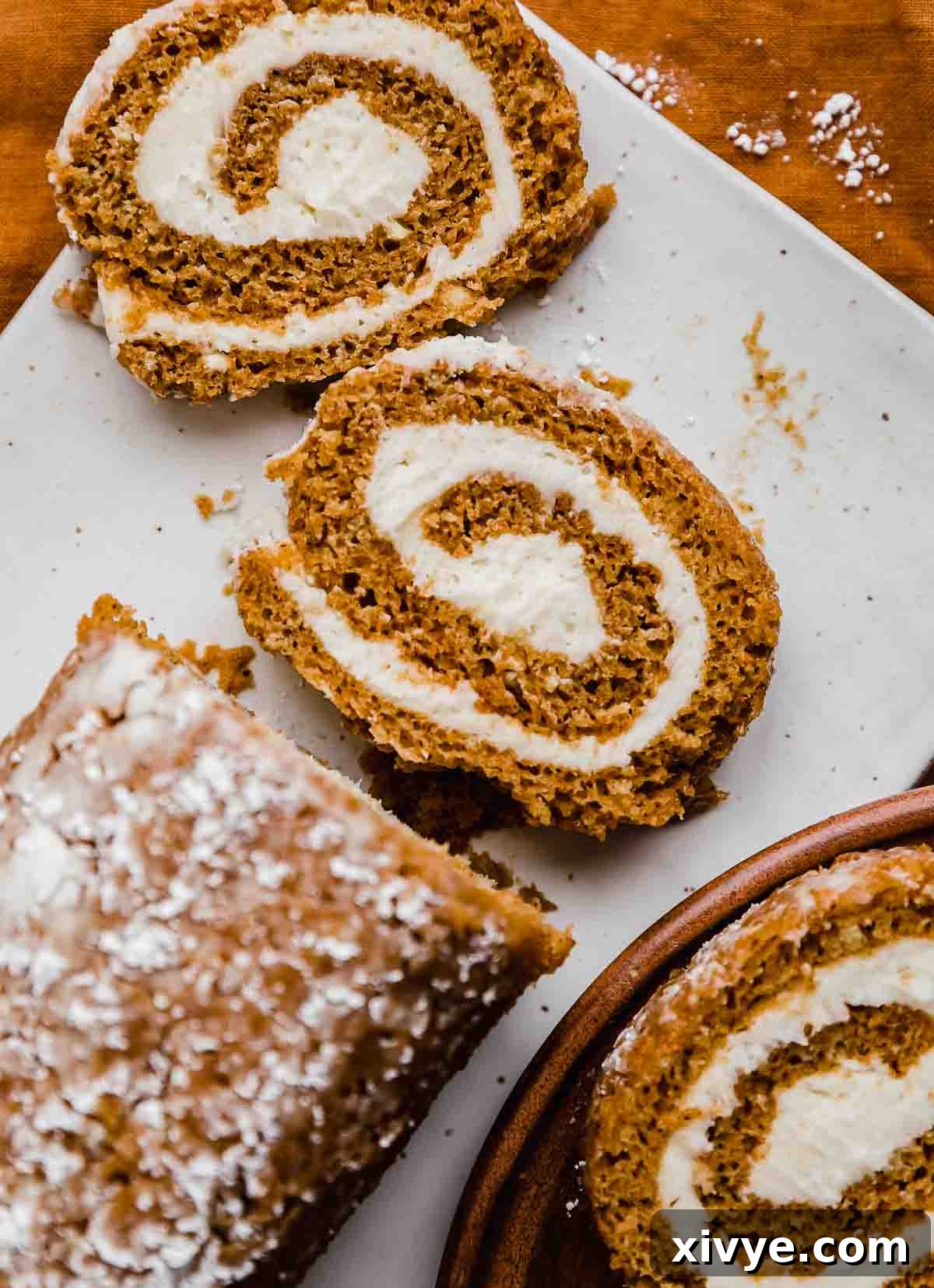 Perfect Pumpkin Cream Cheese Roll 9 Libby's Pumpkin Roll cut into three perfect slices on a white rectangular plate, showcasing the beautiful spiral of cake and cream cheese.
