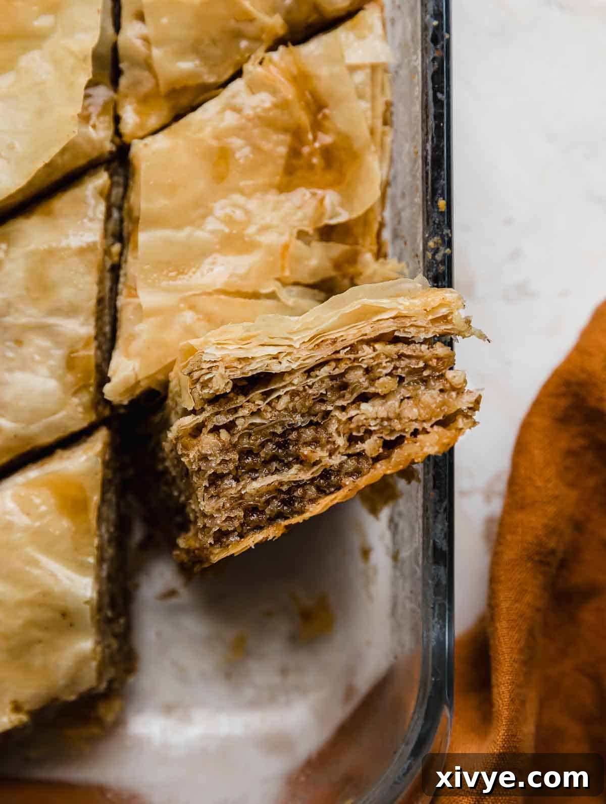 Honeyed Layers of Greece 8 Flaky Greek Baklava cut into diamond shapes, on its edge, showcasing the interior flaky crushed walnut mixture in the baklava recipe.