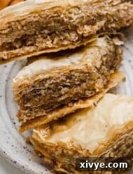 Three Greek Baklava pastries on a white plate, showcasing their golden layers.
