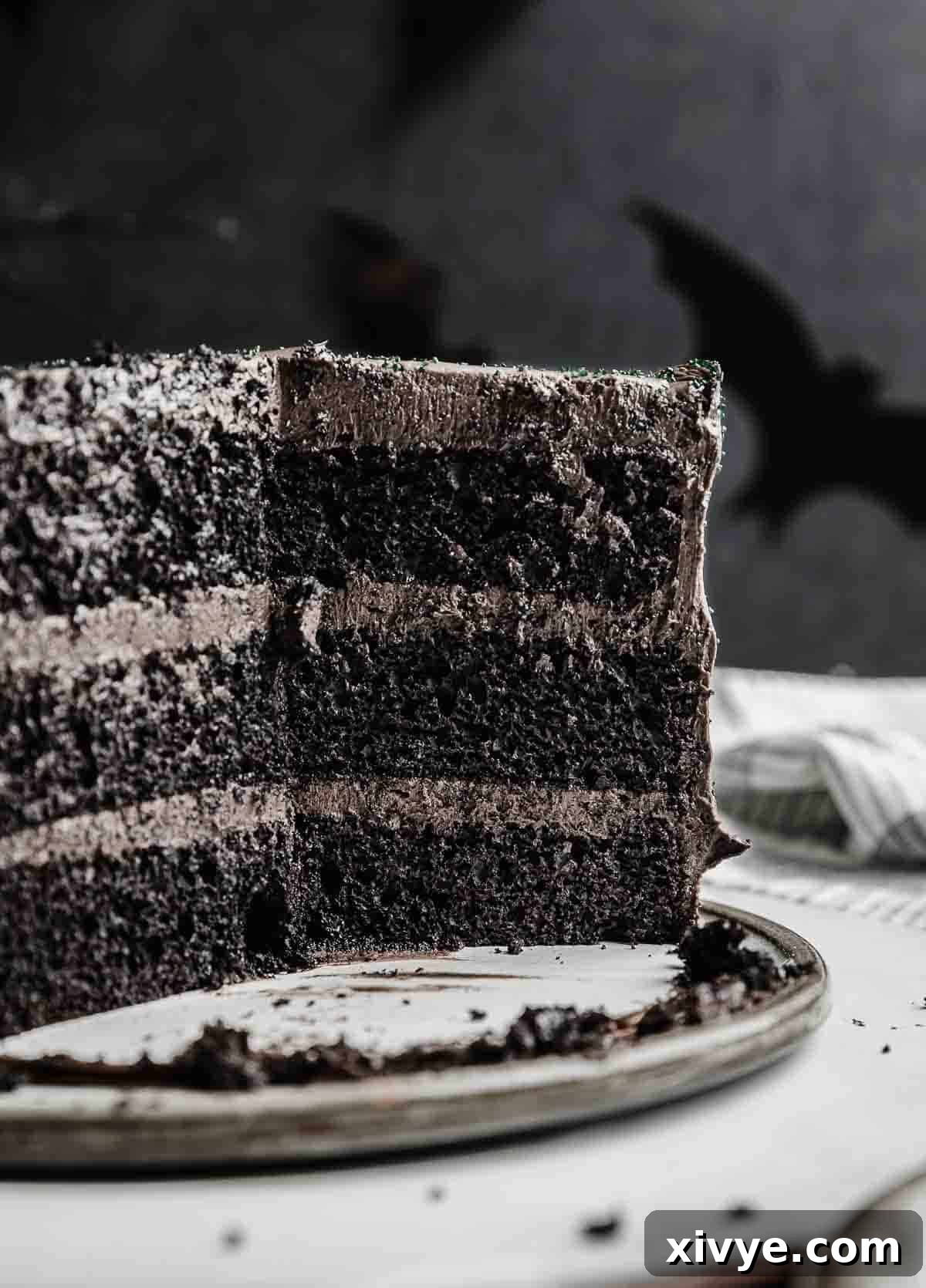 A Black Velvet Cake, expertly layered, with several slices removed to reveal the moist, dark interior of the three-tiered cake.