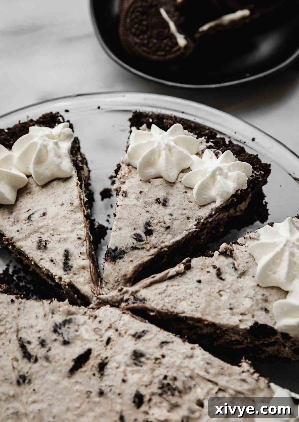 Cookies and Cream Pie cut into triangle slices and topped with whipped cream.