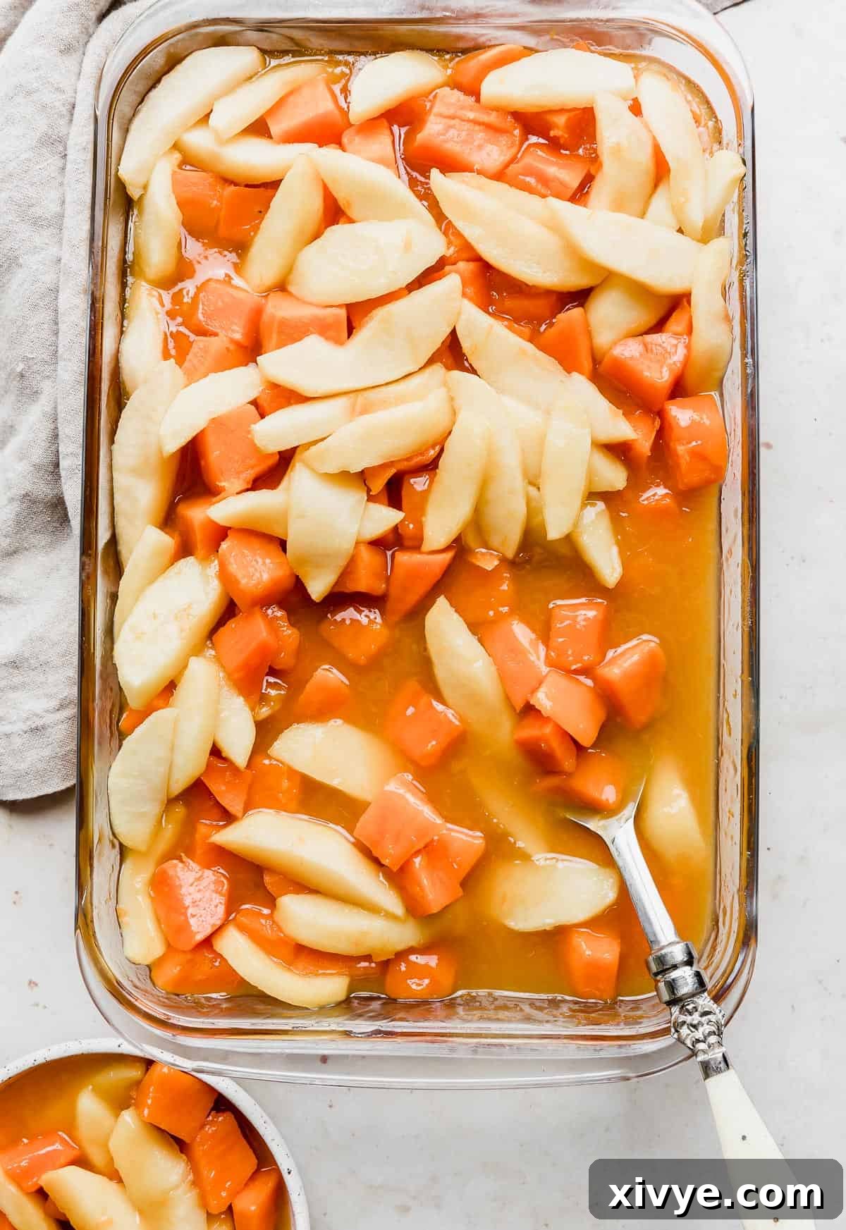 Beautifully prepared Candied Yams with Apples in a clear glass baking dish, set against a pristine white background, showcasing its festive appeal.