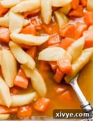 Orange juice candied yams in a baking dish topped with apples, showcasing the golden glaze and tender fruit.