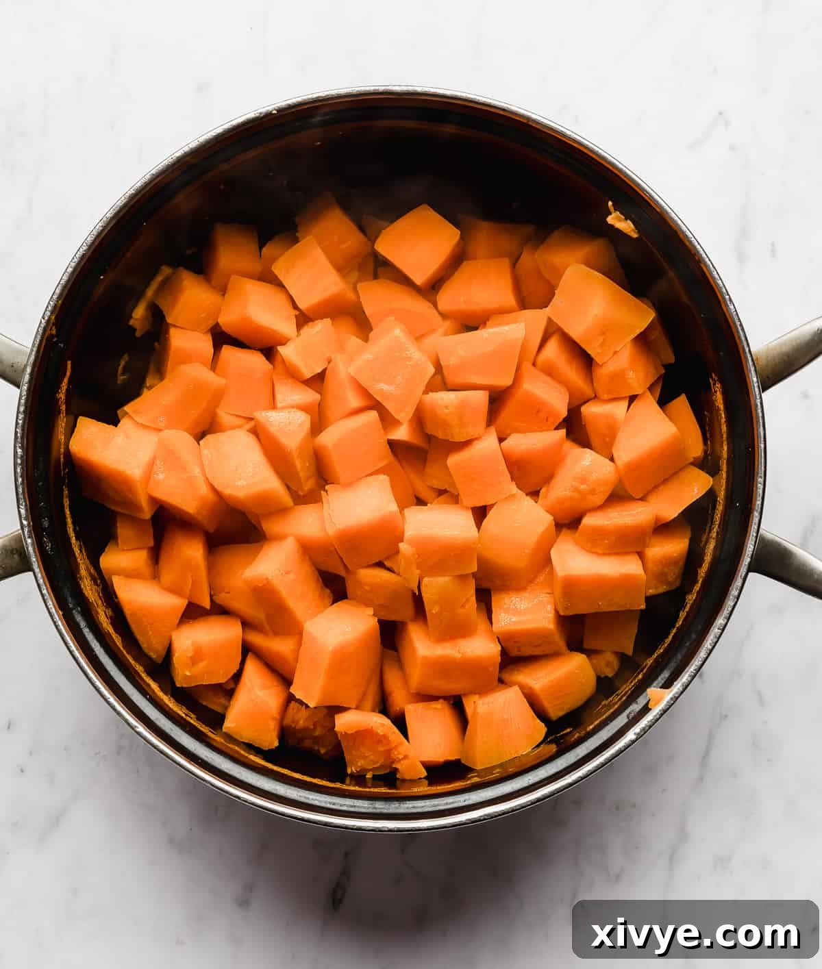 A large black pot filled with cooked, cubed sweet potatoes, showcasing their tender texture.