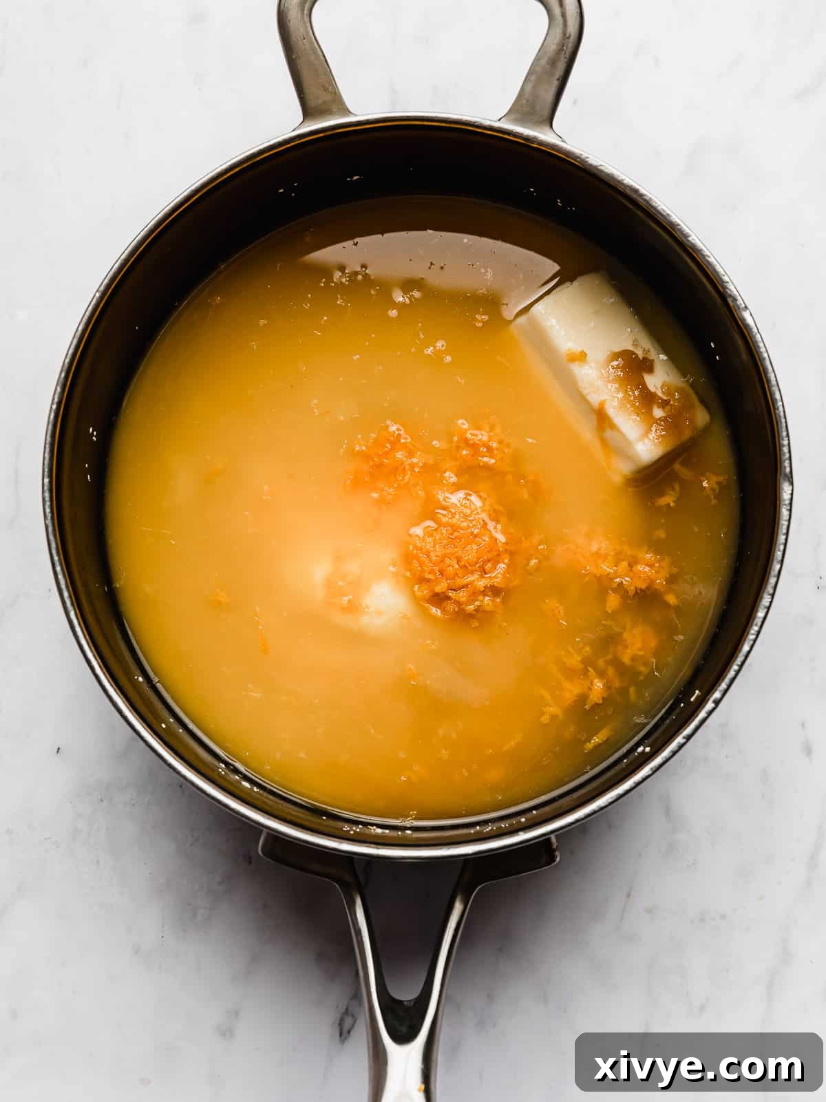 A rich, thick orange candied yams sauce simmering gently in a black saucepan.