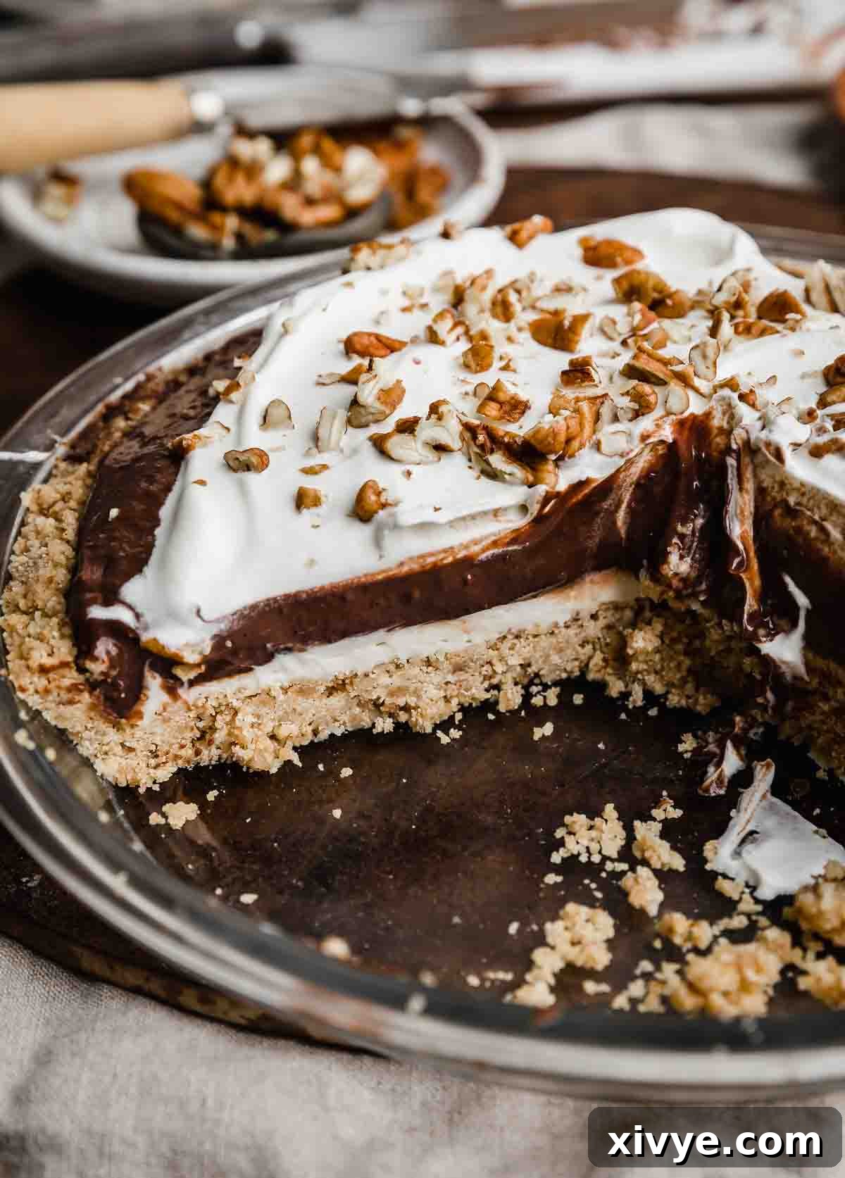An Arkansas Possum Pie sliced into, showing the pecan shortbread crust topped with cream cheese filling, chocolate pudding then a whipped topping.