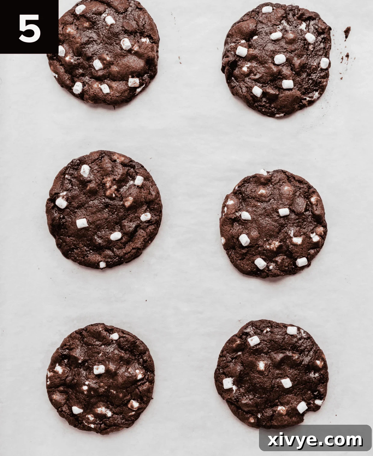 Baked hot chocolate cookies on a white parchment paper covered baking sheet.