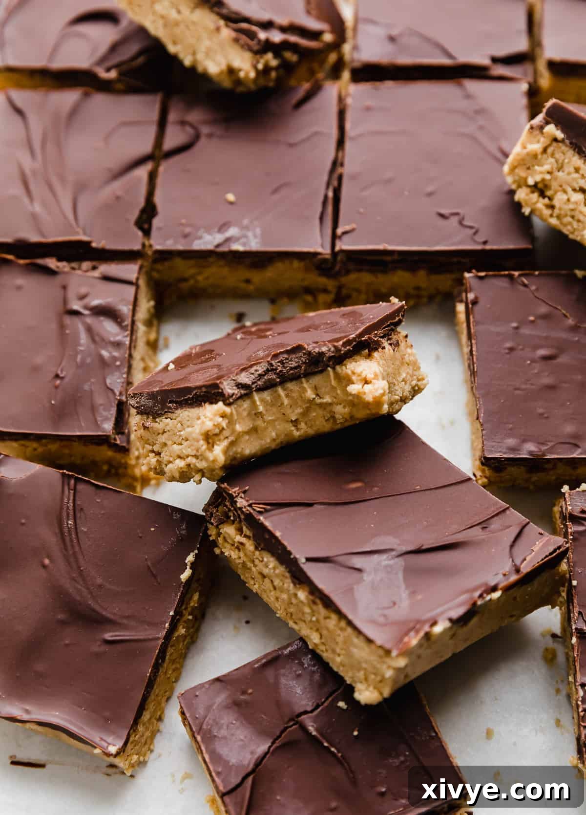 Irresistible Chocolate Peanut Butter Bliss 6 Sliced Chocolate Peanut Butter Bars arranged on a white background, with one bar having a bite taken out of it, revealing the distinct layers of chocolate and peanut butter.
