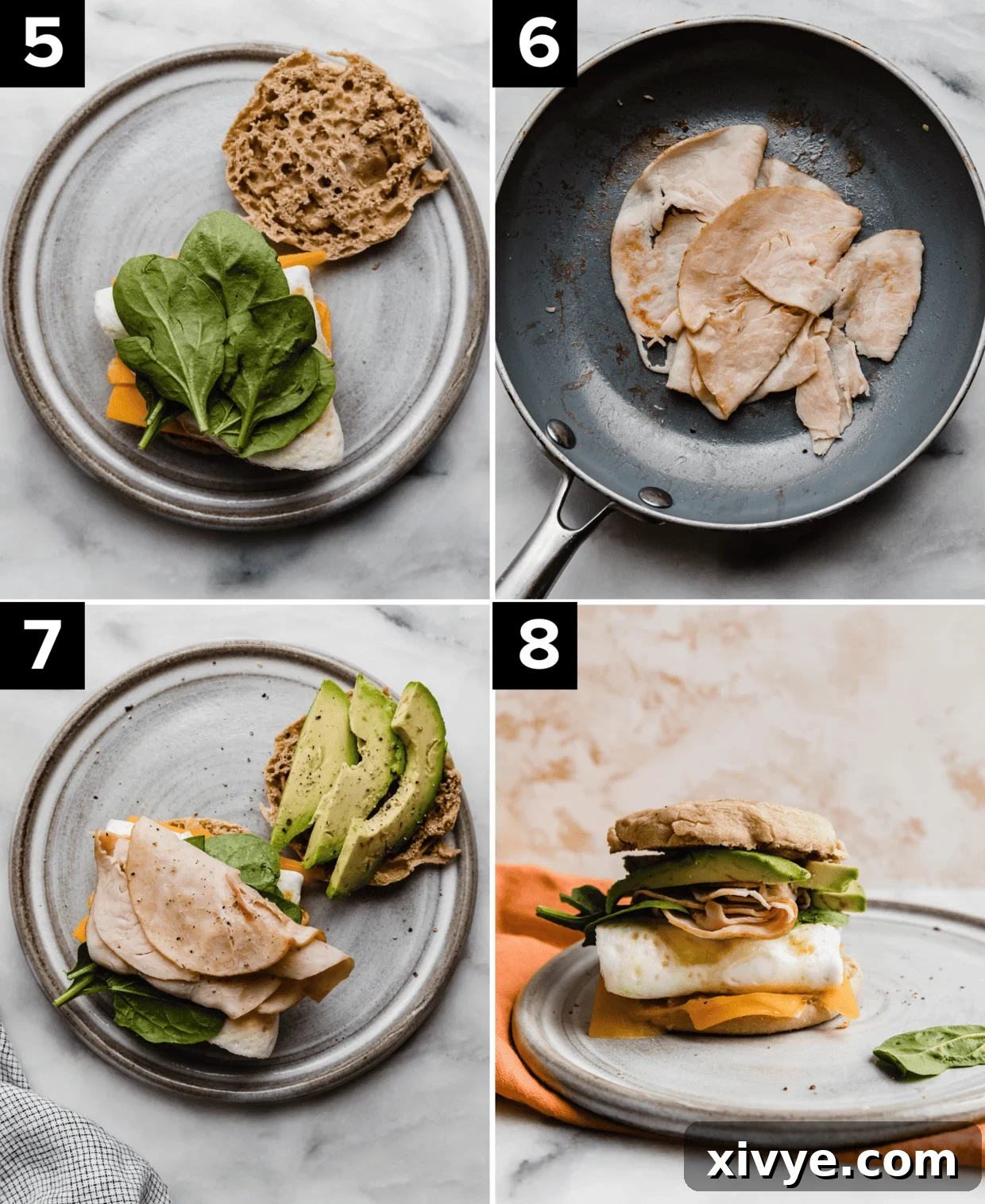 Warm deli turkey meat being transferred from a skillet onto an English muffin already layered with avocado, fresh spinach, cooked eggs, and melted cheese.