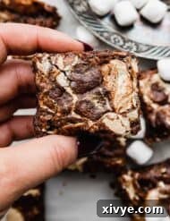 A hand holding a Marshmallow Brownie that has marshmallow cream/fluff that was swirled into the top of the brownie before baking.