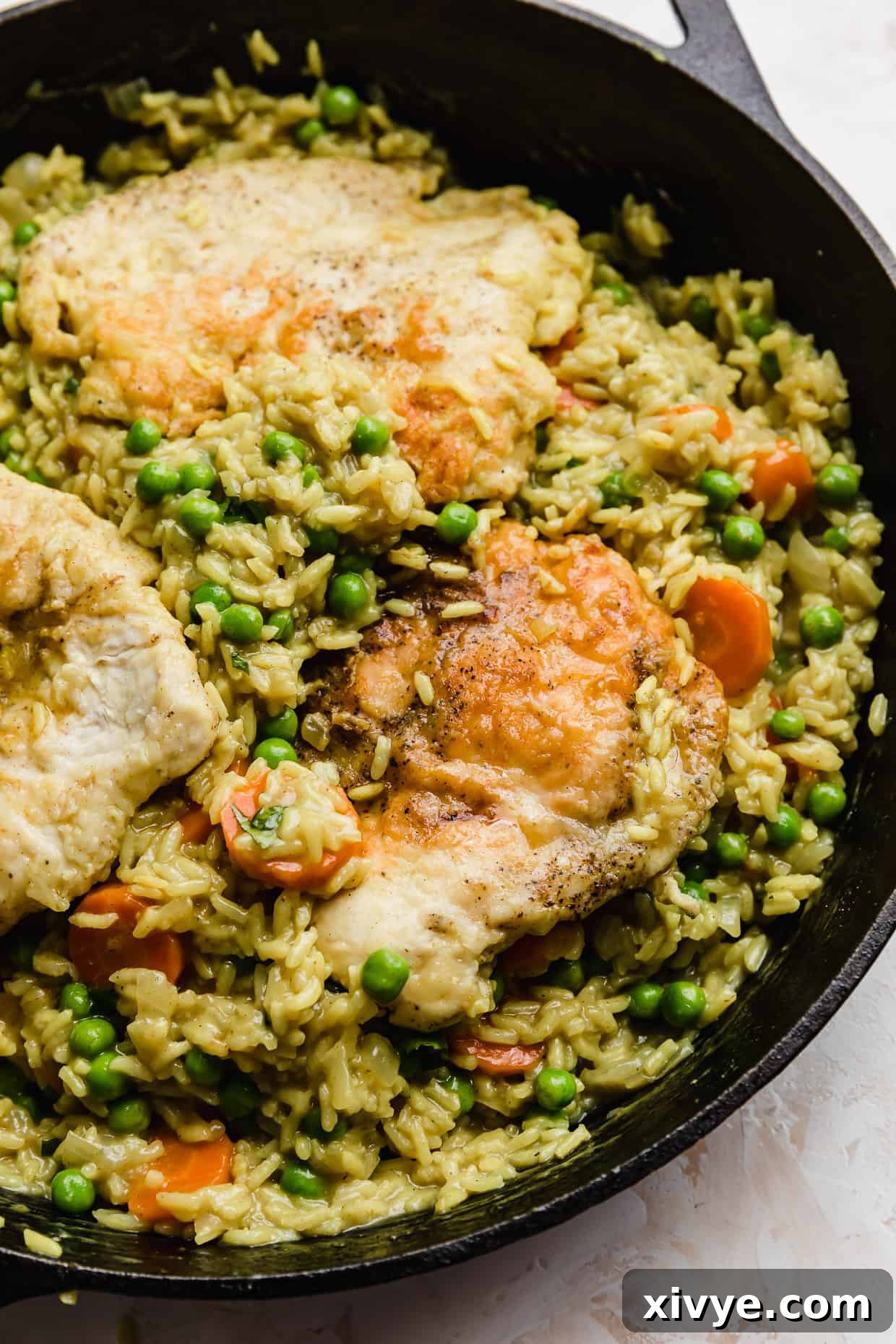 Caribbean Curried Chicken with Coconut Rice and Beans 2 A black skillet with Curry Chicken Rice and Peas and carrots in it, ready to be served.