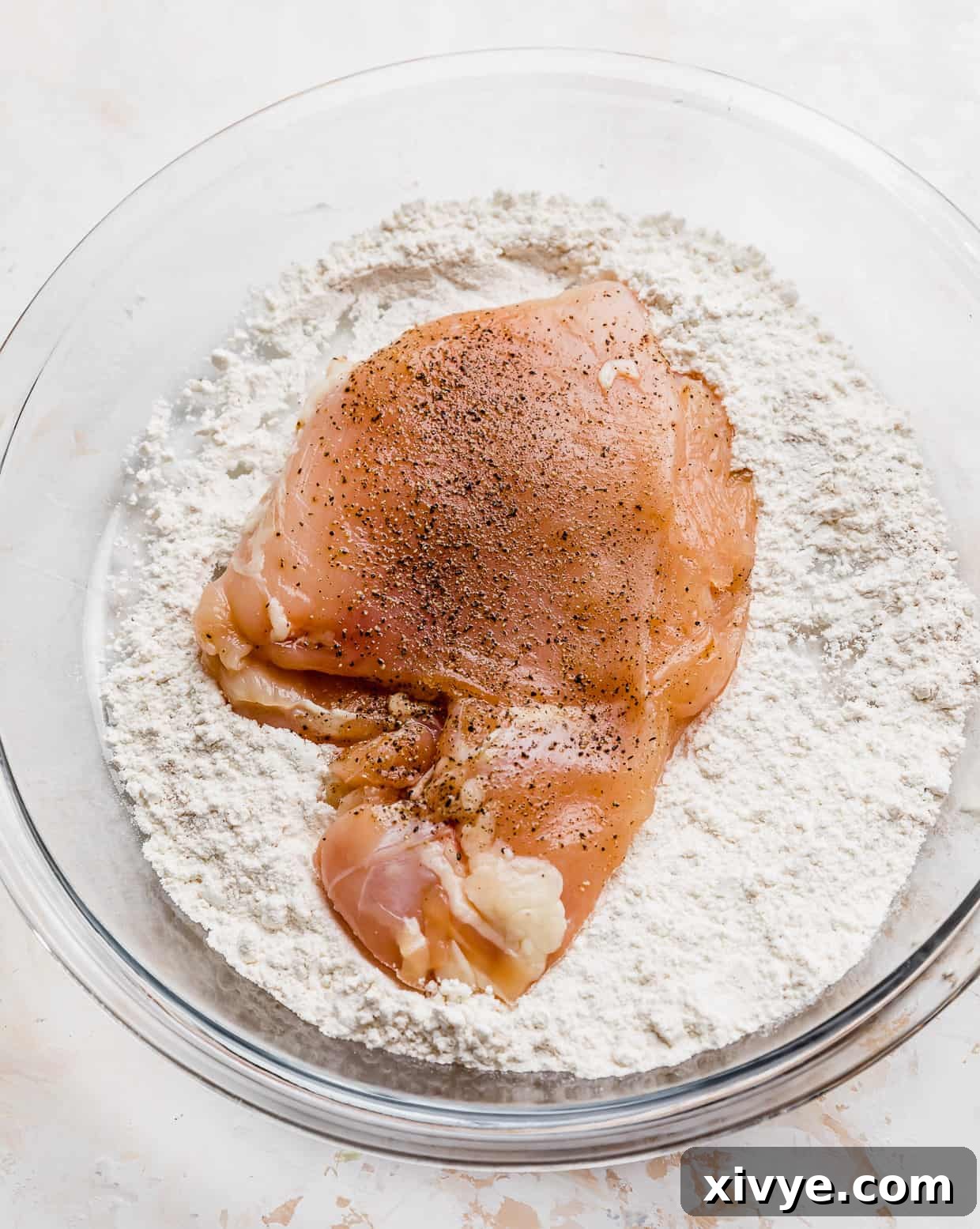 Caribbean Curried Chicken with Coconut Rice and Beans 4 Raw chicken breast in a flour filled pie plate, being dredged for cooking.