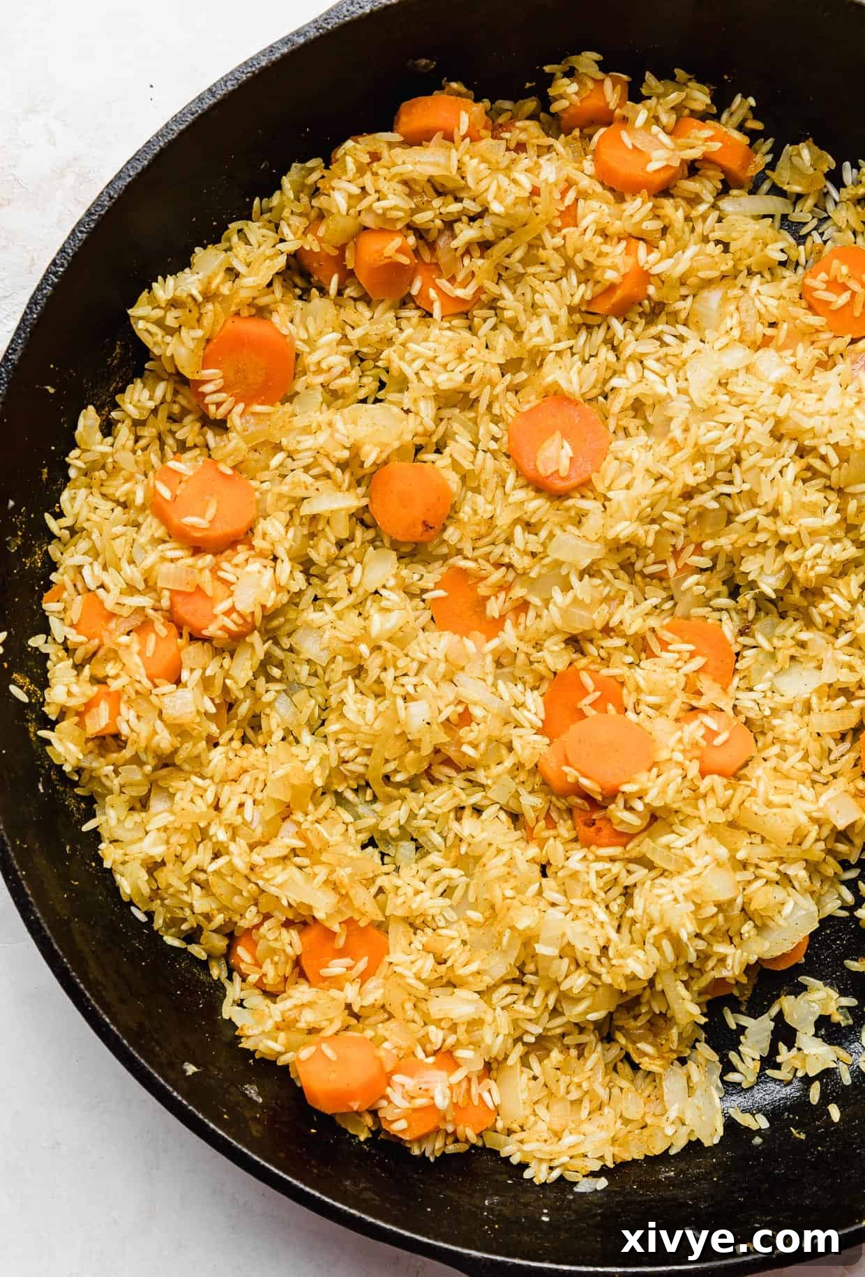 Caribbean Curried Chicken with Coconut Rice and Beans 6 Carrots and rice being sautéed in a black skillet.