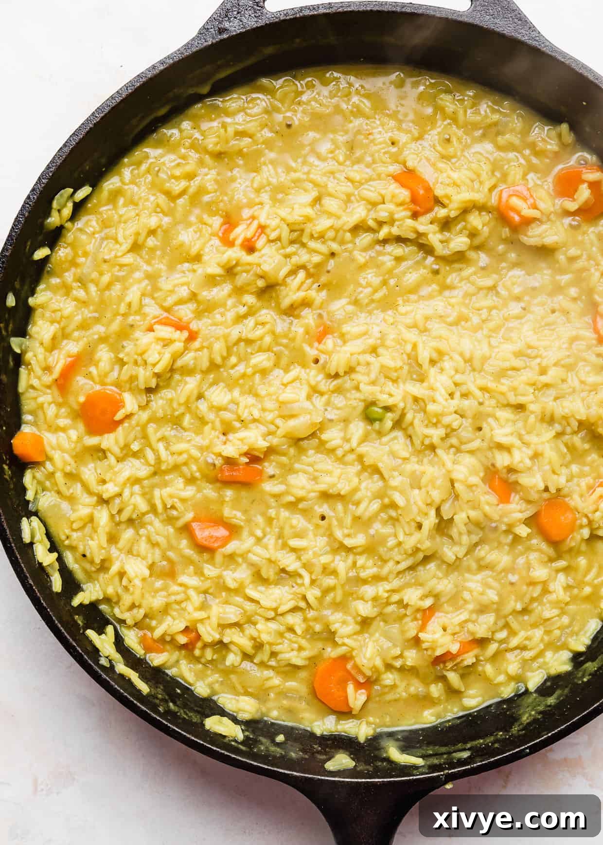 Caribbean Curried Chicken with Coconut Rice and Beans 7 Rice and carrots mixed with curry spices simmering in a skillet with chicken broth.