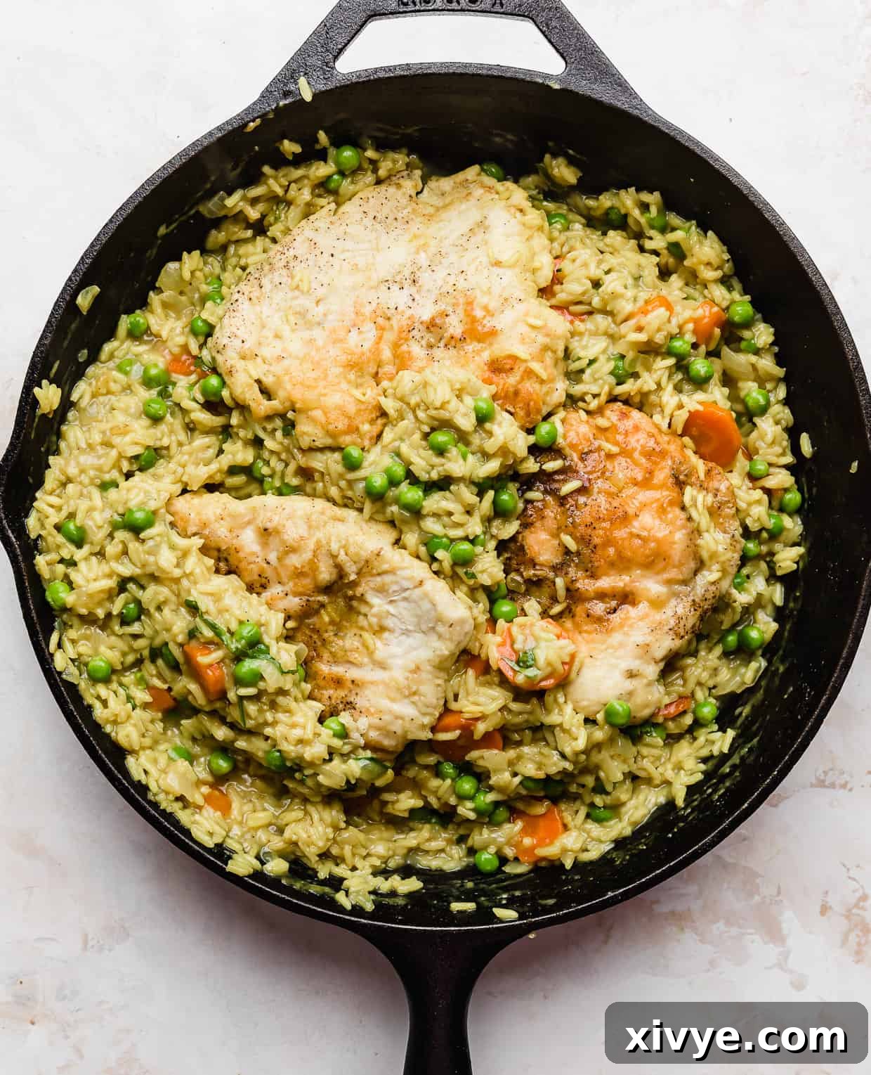 Caribbean Curried Chicken with Coconut Rice and Beans 10 Curry Chicken Rice and Peas and carrots in a black skillet on a white background, highlighting its delicious appearance.