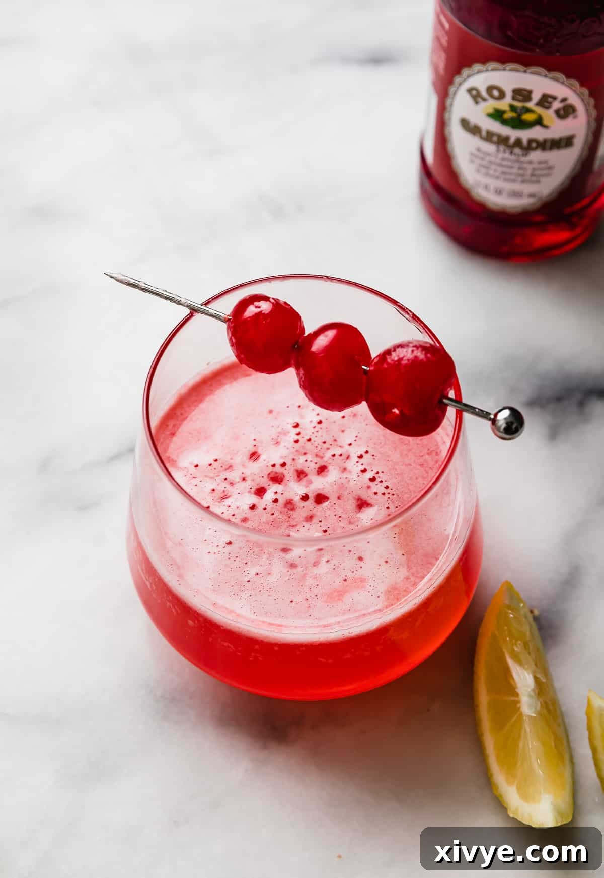 Pink Elegance Sparkler 5 Pink Lady Mocktail in a small glass with three maraschino cherries on a cocktail stick.