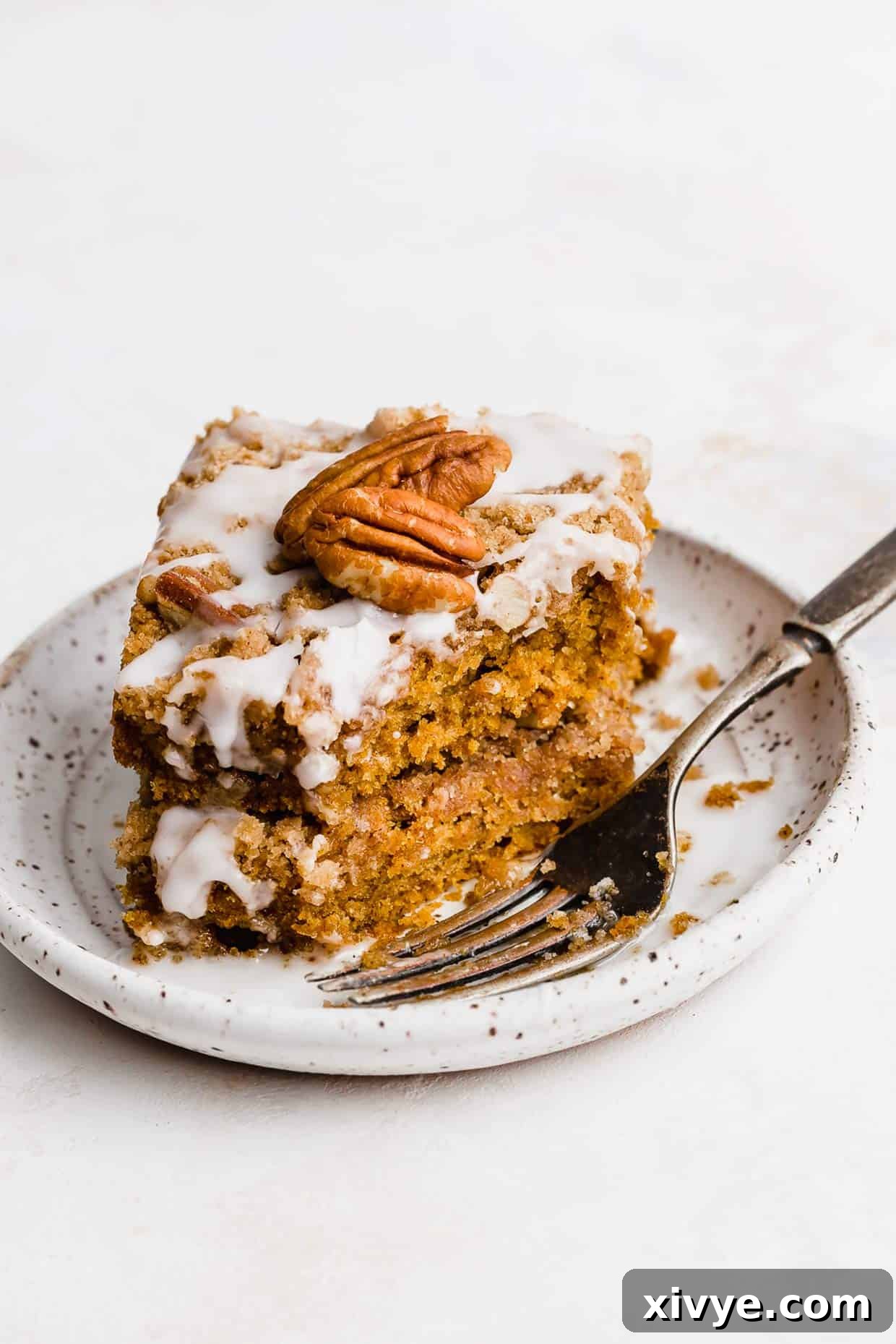 Golden Pumpkin Pecan Crumble Coffee Cake 2 Two generous slices of glazed pumpkin coffee cake, layered on a pristine white plate, showcasing the moist interior and crunchy pecan streusel.