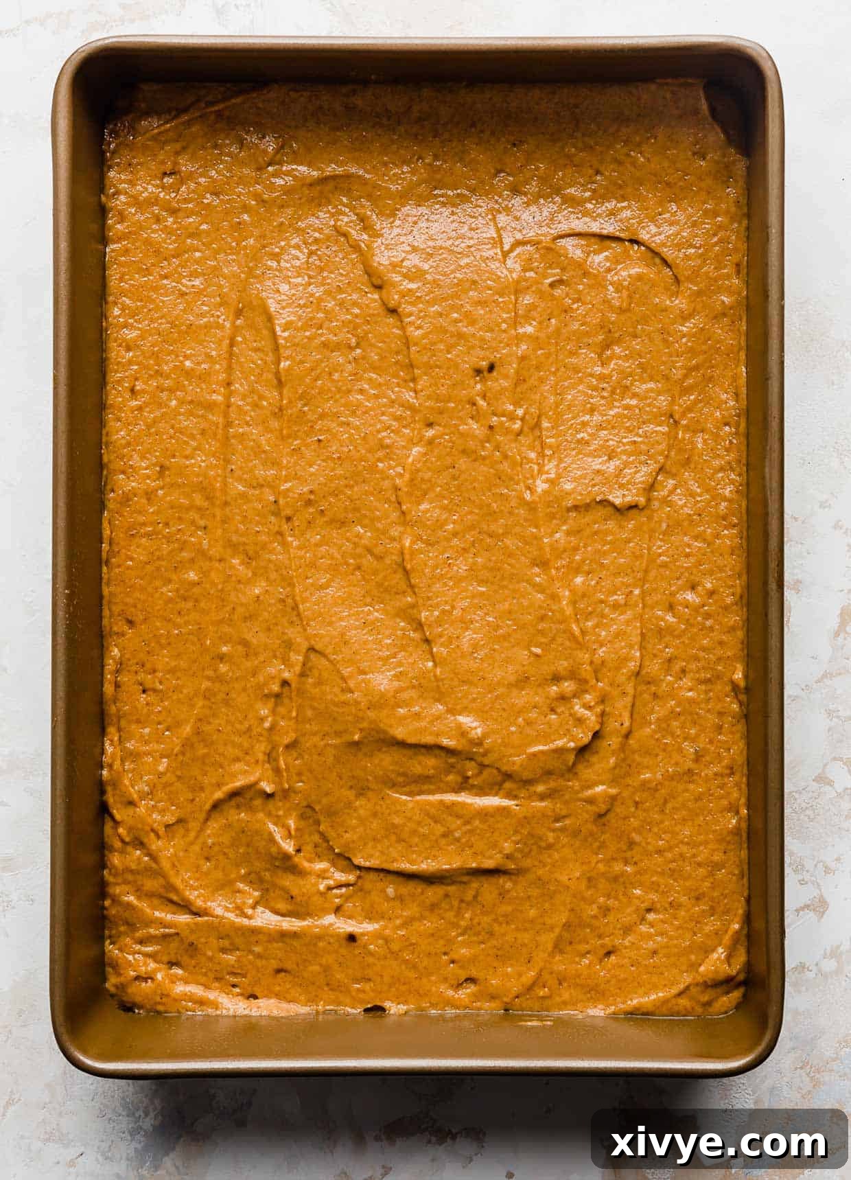 Golden Pumpkin Pecan Crumble Coffee Cake 5 Vibrantly orange pumpkin coffee cake batter smoothed into a bronze 9x13 inch baking pan, ready for its topping.