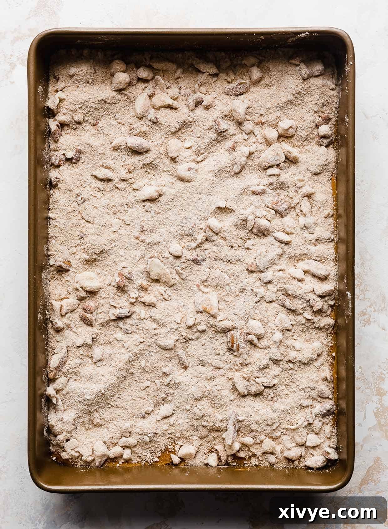 Golden Pumpkin Pecan Crumble Coffee Cake 6 The unbaked pumpkin coffee cake, generously covered with a rich pecan streusel topping, showcasing the raw ingredients before baking.