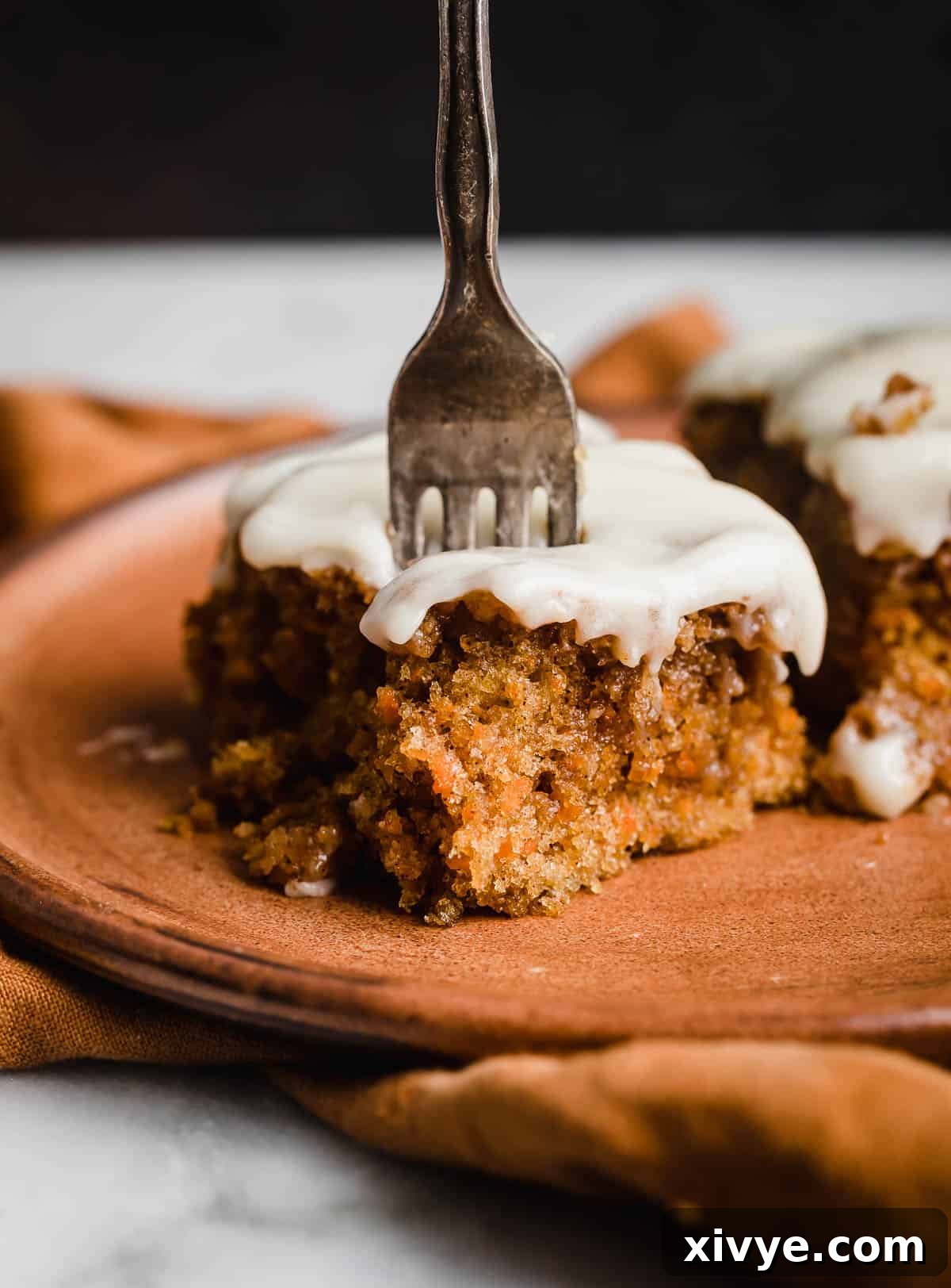 Spiced Carrot Crumb Cake 9 A fork cutting into a slice of moist carrot cake coffee cake on a brown plate.