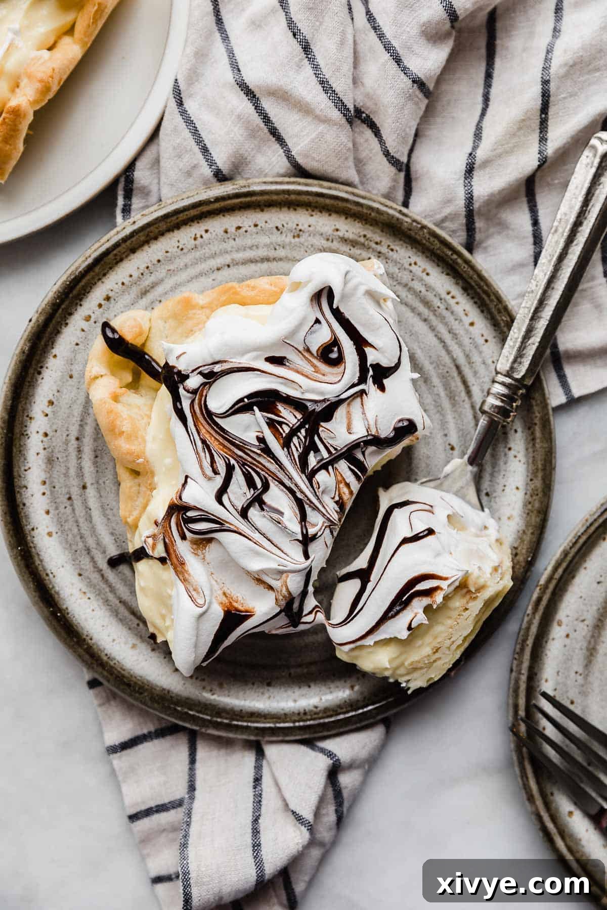 Overhead photo of the best cream puff cake on a gray plate resting on a tan and blue striped linen napkin.
