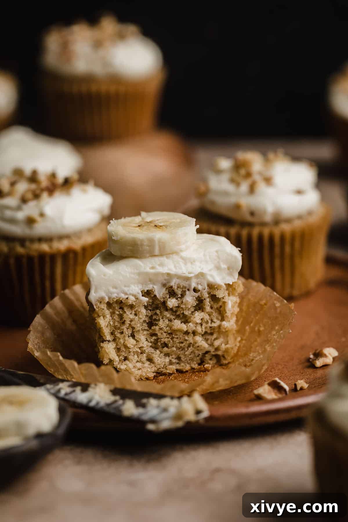 Delicious Homemade Banana Cupcakes 6 A perfectly sliced banana cupcake revealing its moist crumb, generously topped with a swirl of delicate cream cheese frosting.