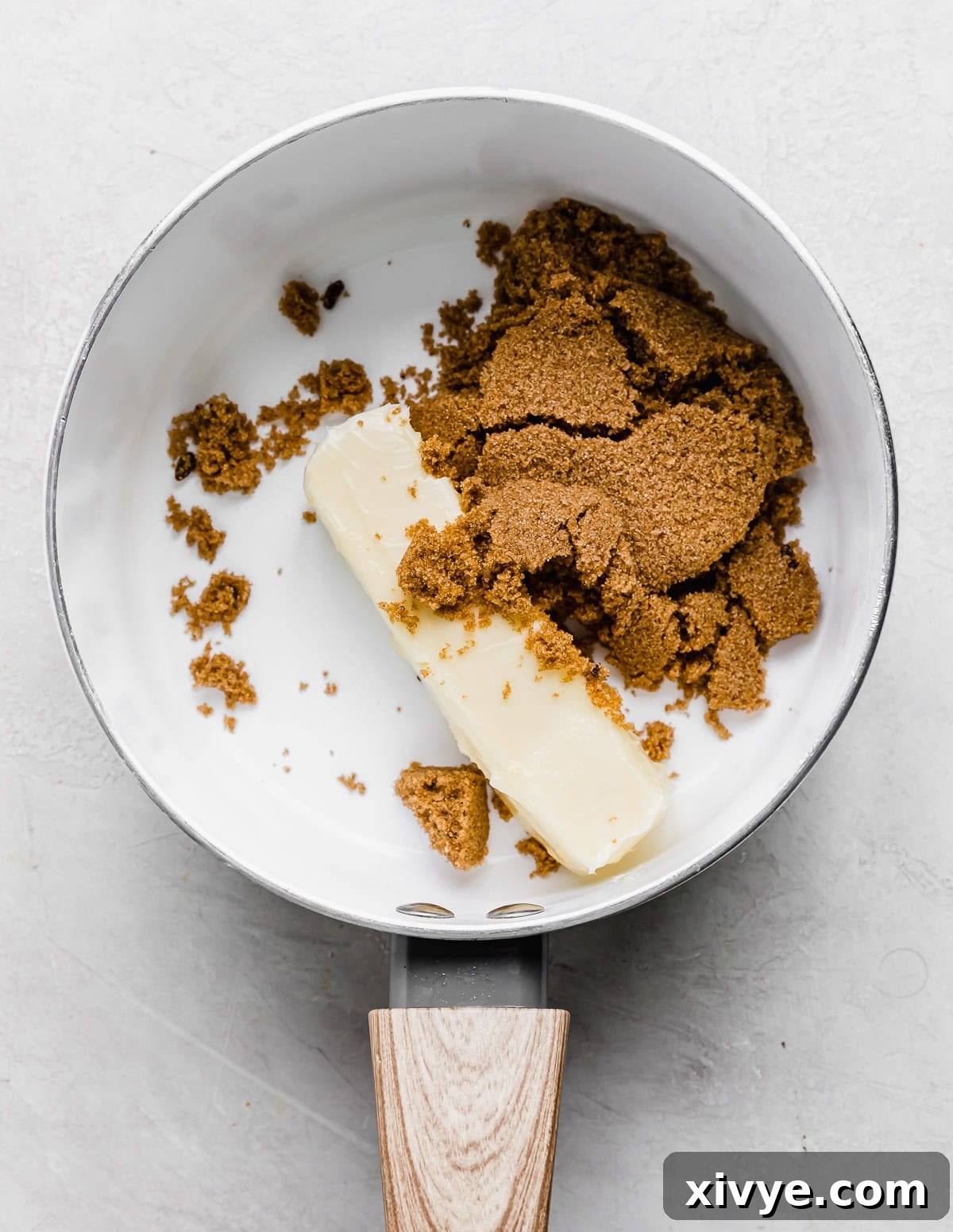 Decadent Banoffee Pie with Crunchy Graham Crust 5 A stick of butter and dark brown sugar in a white saucepan.